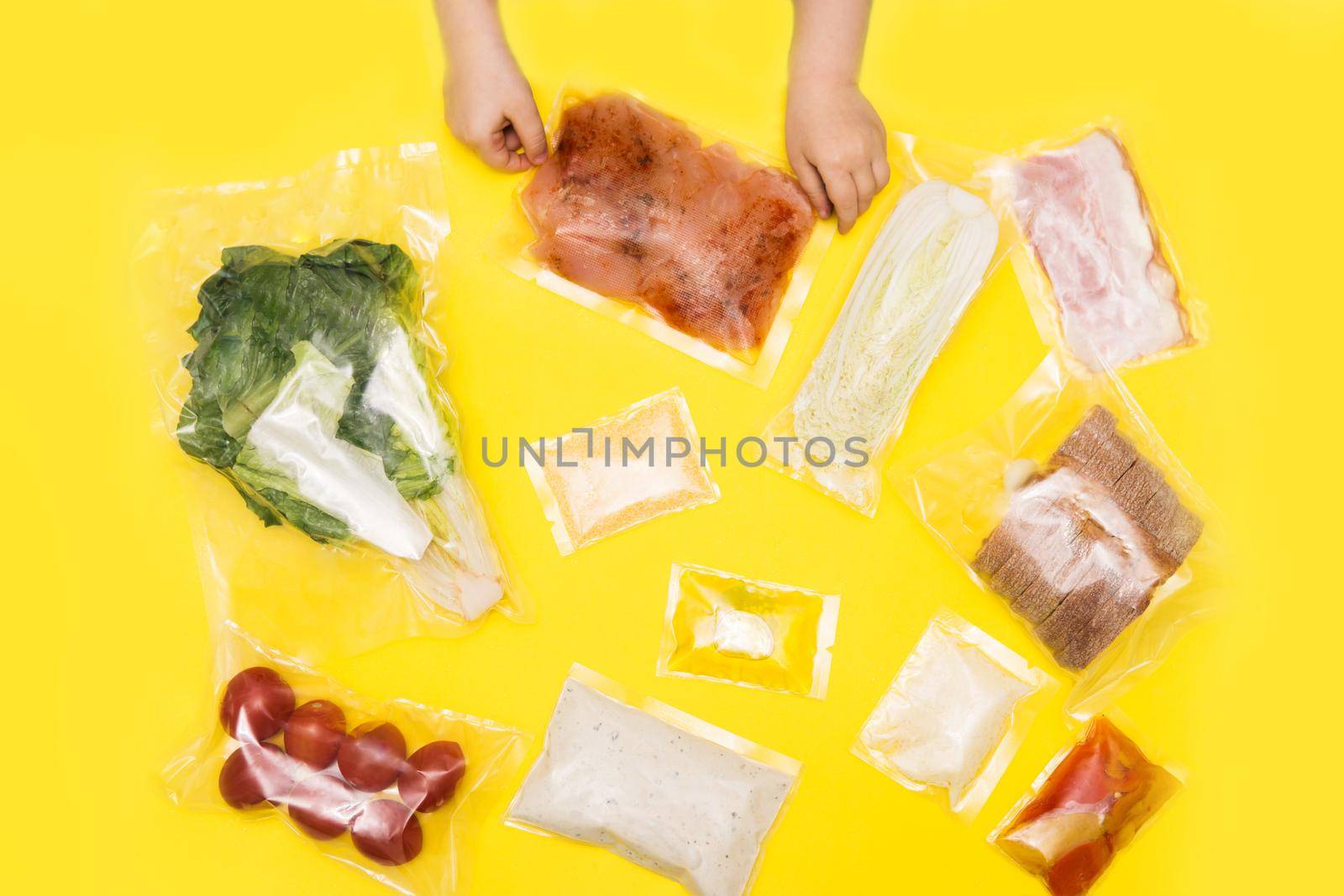 Hands holding bags of food. Salad dinner set: chicken, lettuce, tomatoes, peking cabbage, cheese, bacon, bread, olive oil sauces and spices. Set for delivering food for dinner on yellow background. I cook at home.