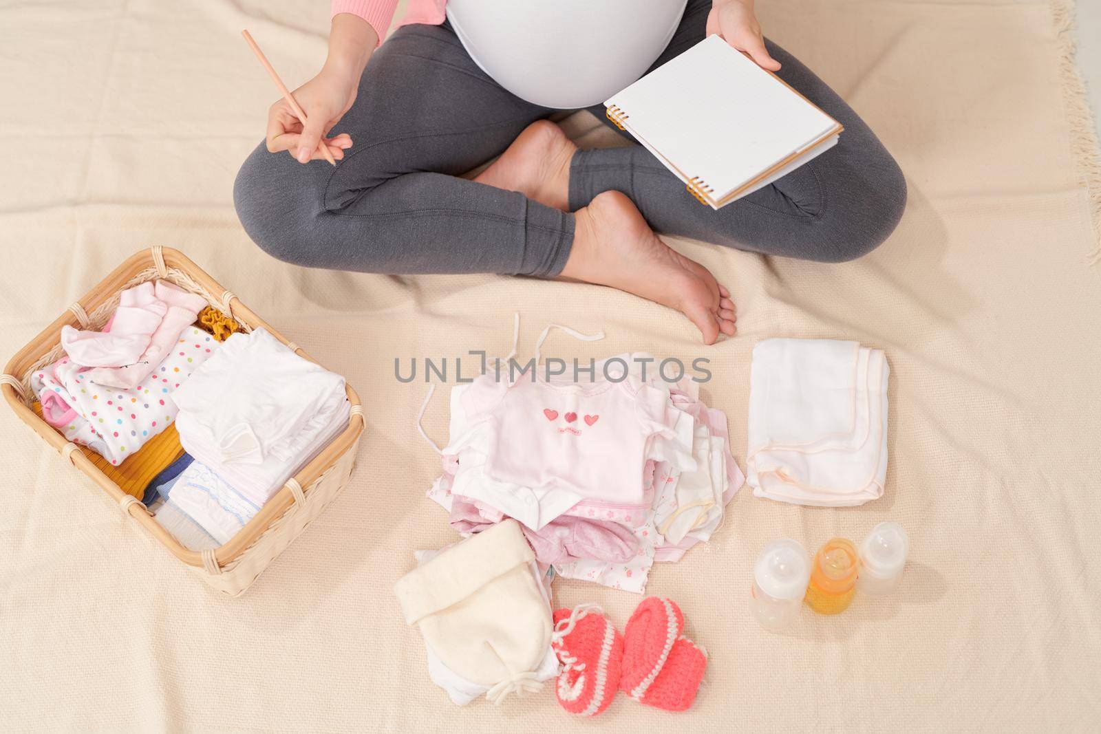 Happy young mother with travel luggage of baby clothes at home