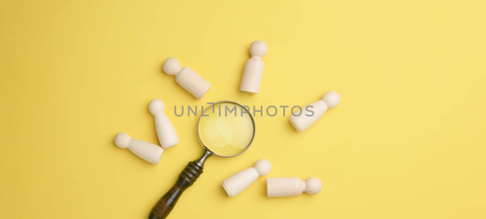 wooden men and a magnifying glass on a yellow background. Recruitment concept, search for talented and capable employees, career growth by ndanko