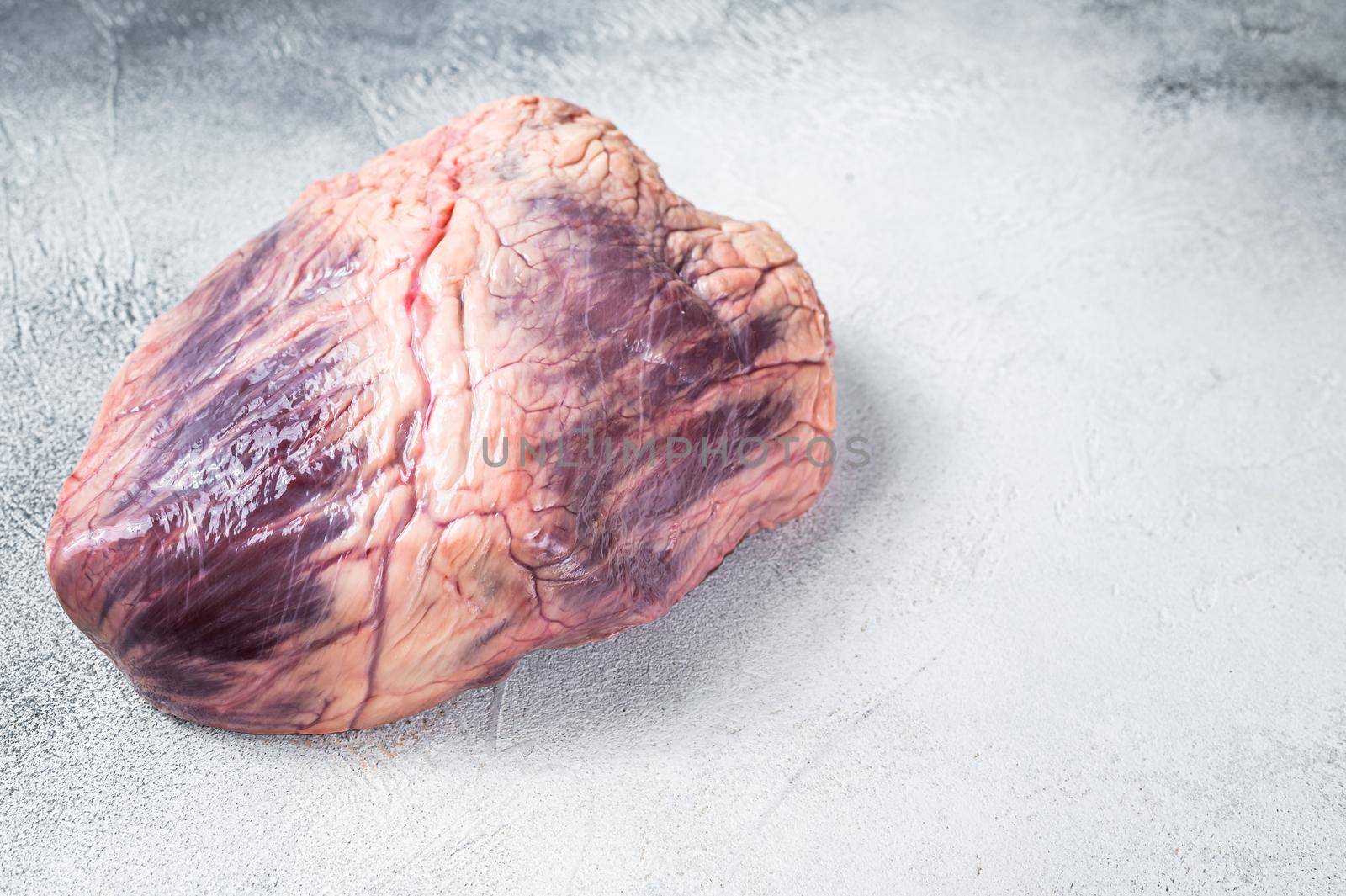 Beef or veal raw heart on a butcher table. White background. Top View. Copy space.