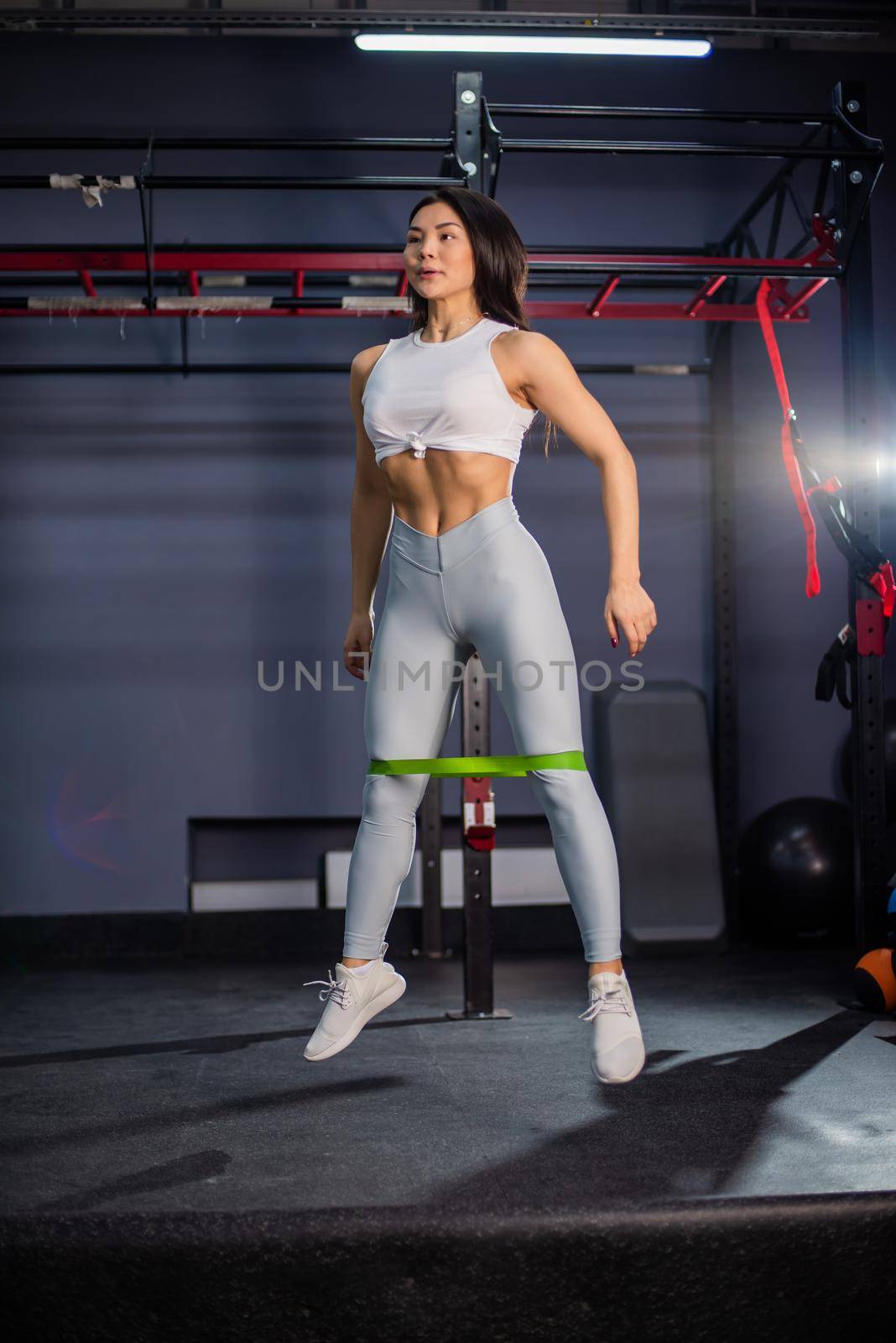 Asian woman doing exercise with fitness rubber band in the gym.