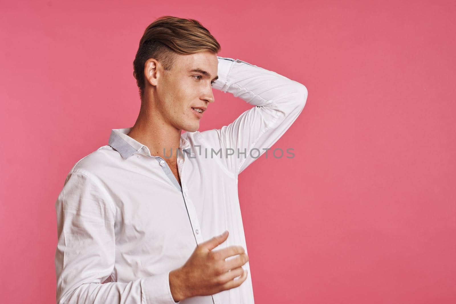 Young man in white shirt posing on pink background. High quality photo