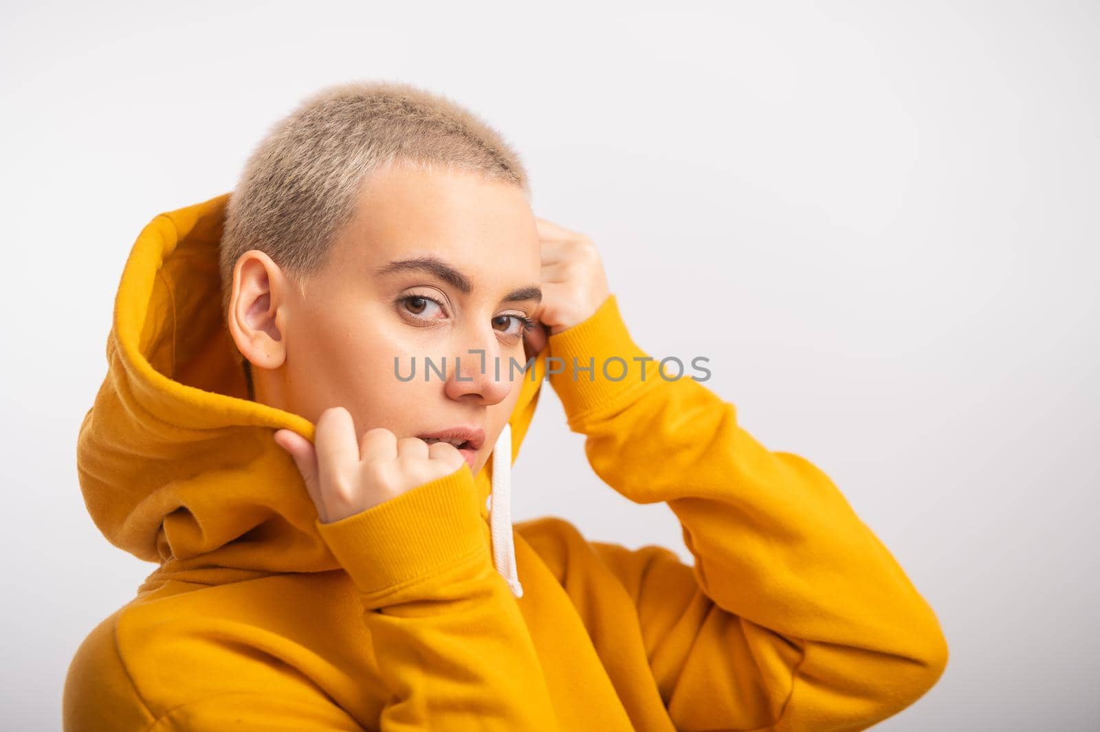 Young woman in an ocher hood on a white background