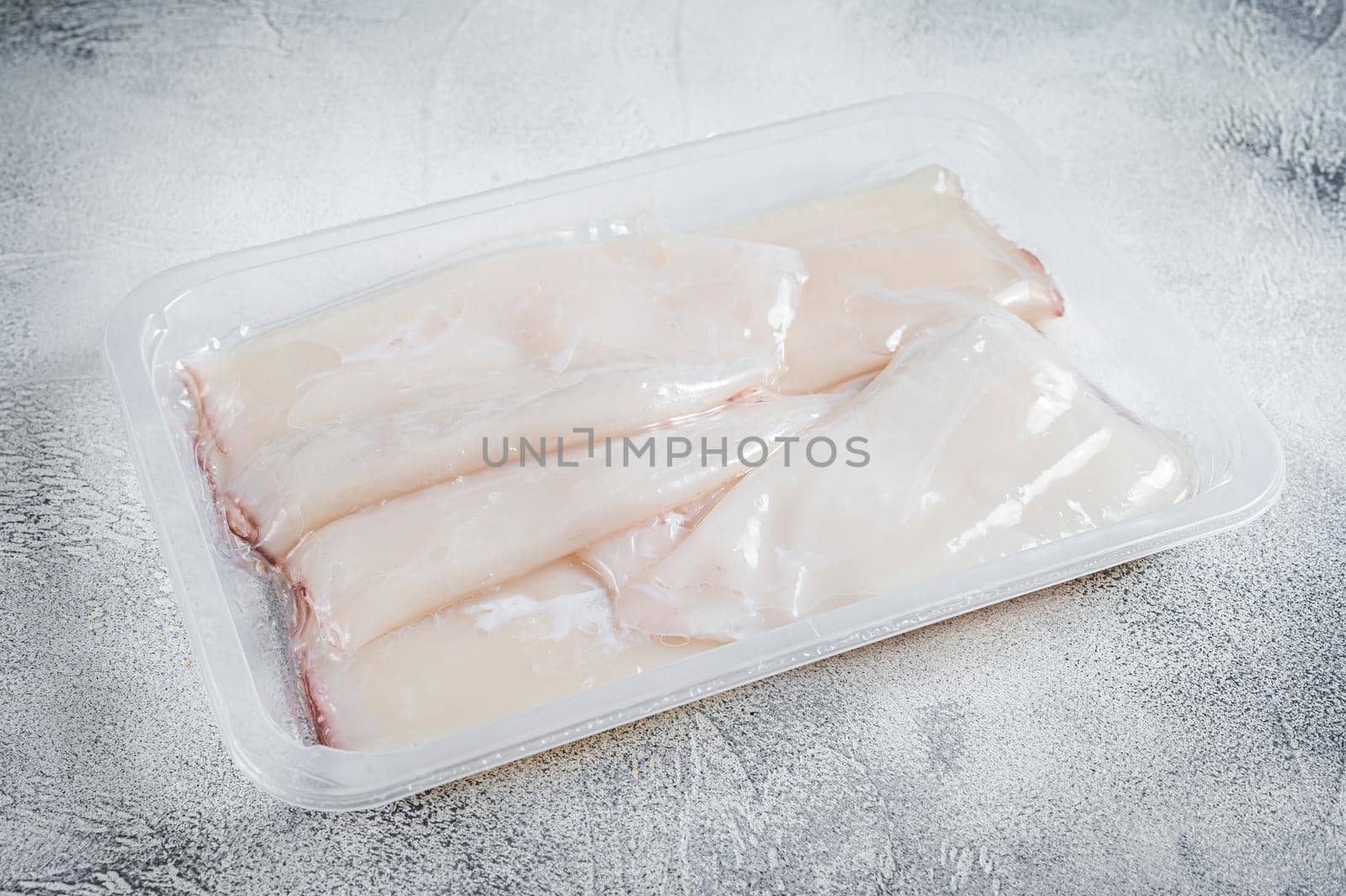 Raw squid or Calamari in a vacuum package from the supermarket. White background. Top view.
