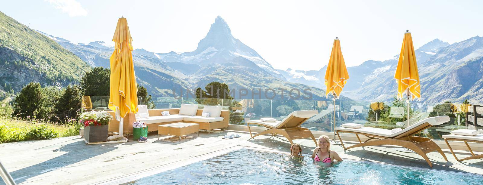 Mother and daughter swimming in outdoor swimming pool in the mountains