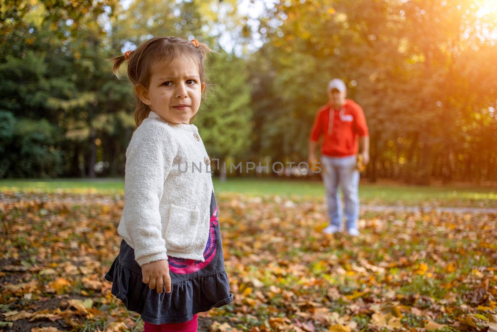 disgruntled child in the park with dad. angry girl in the park looks at the camera. father and daughter Toddler walk in the park by Mariaprovector