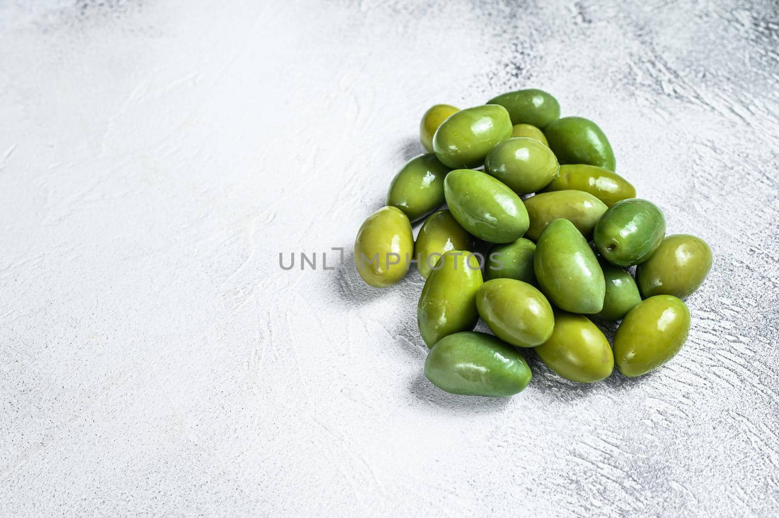 Fresh Green big olives on a table. White background. Top view. Copy space by Composter