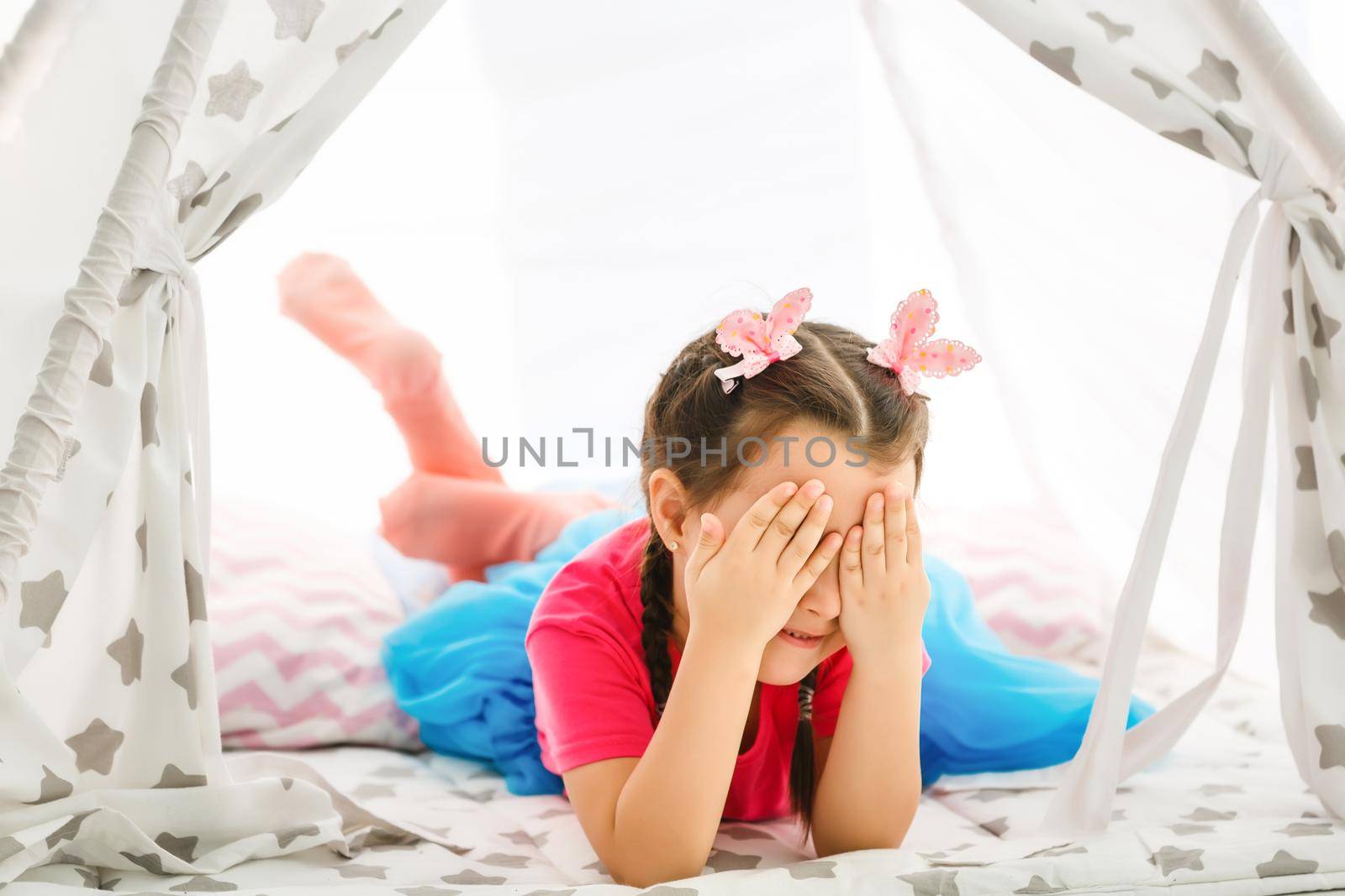 A little girl sits in a wigwam with pillows