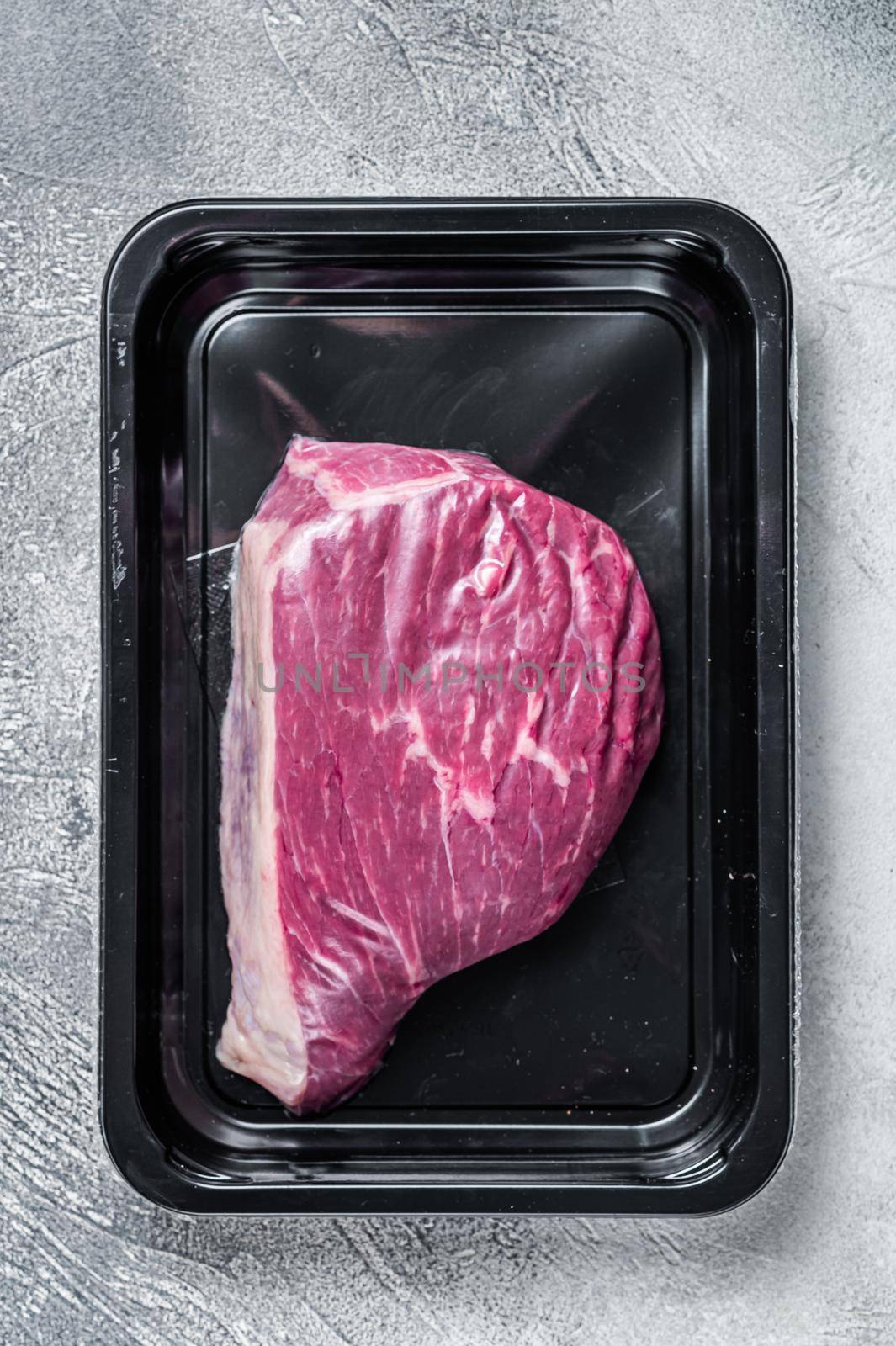 Raw cap rump steak or top sirloin beef meat steak in vacuum packaging. White background. Top view by Composter