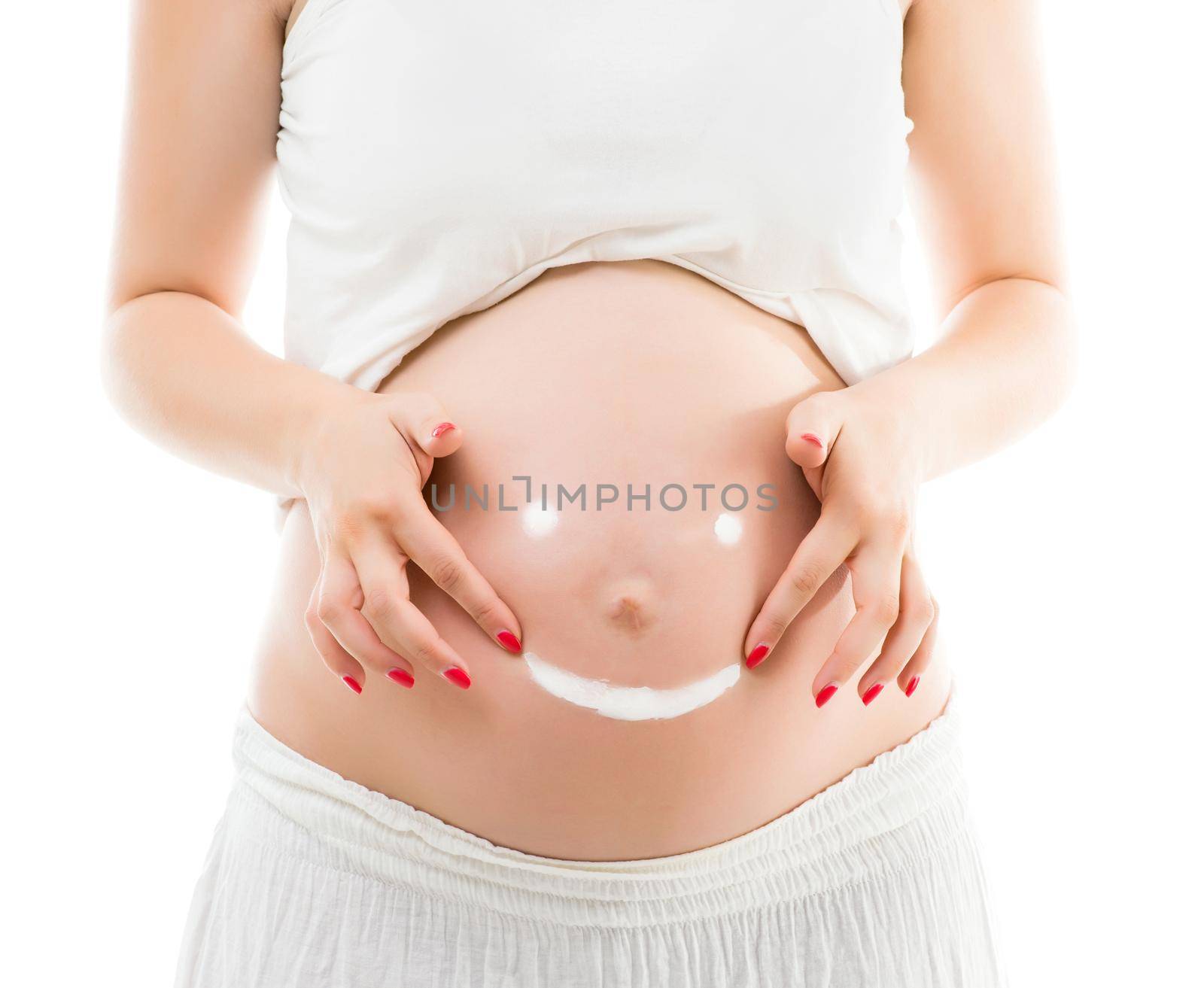 Cream smiley face on the belly of pregnant woman isolated on white background