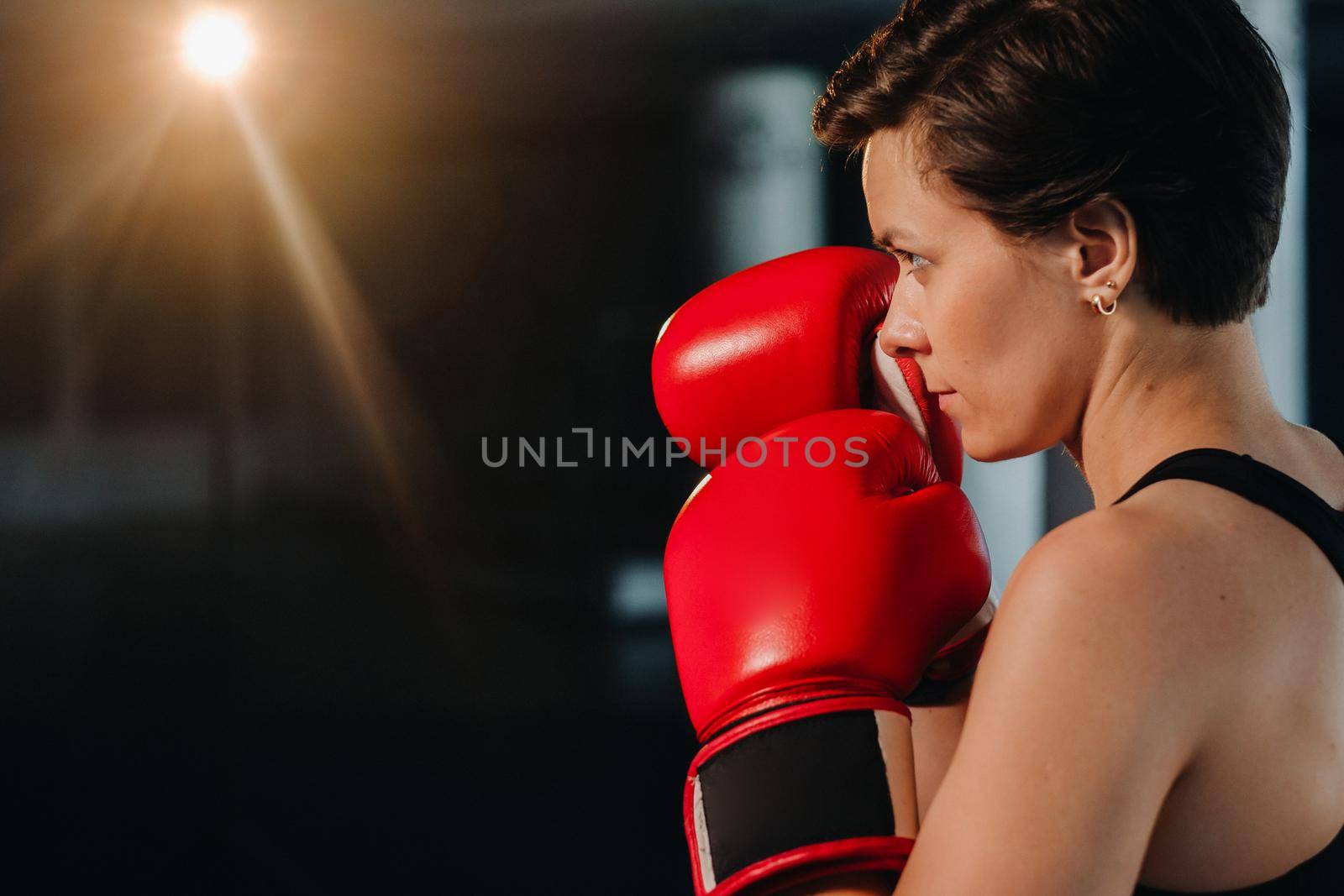 portrait of a female boxer in red gloves in the gym during training.