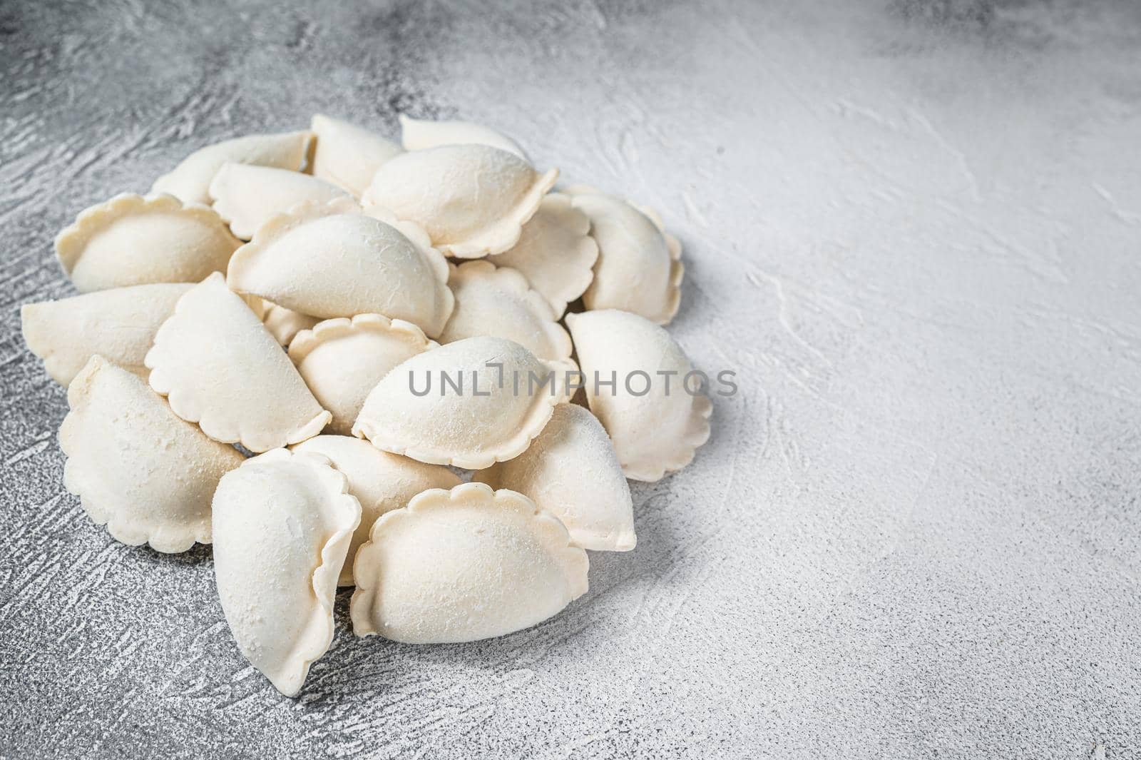 Raw frozen dumplings pierogi on a kitchen table. White background. Top View. Copy space by Composter