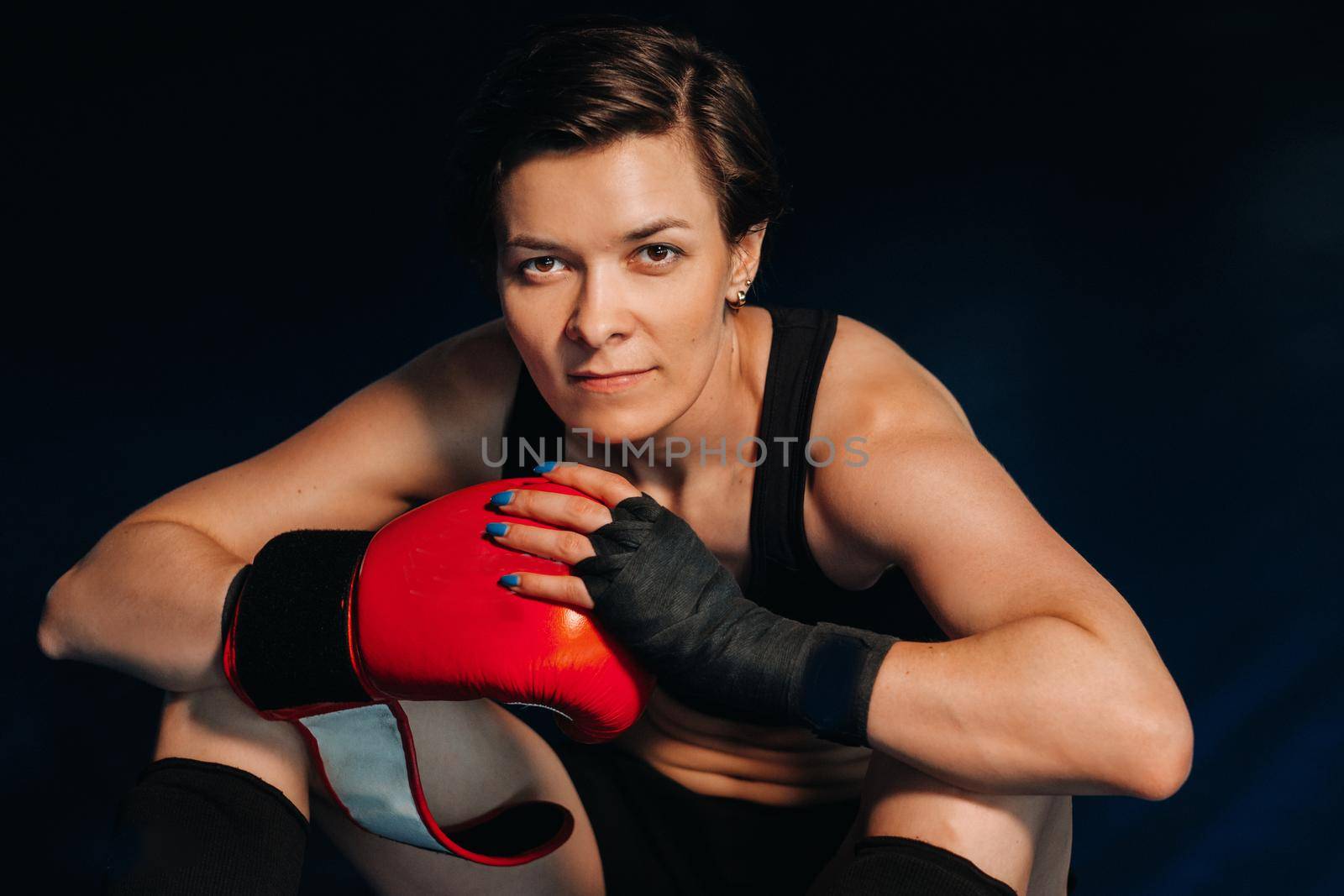portrait of a female boxer in red gloves in the gym after training.