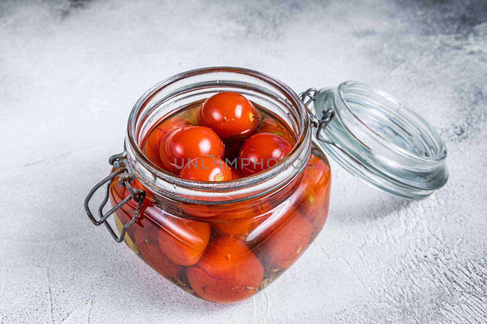Pickled cherry tomatoes in a glass jar. White background. Top view by Composter