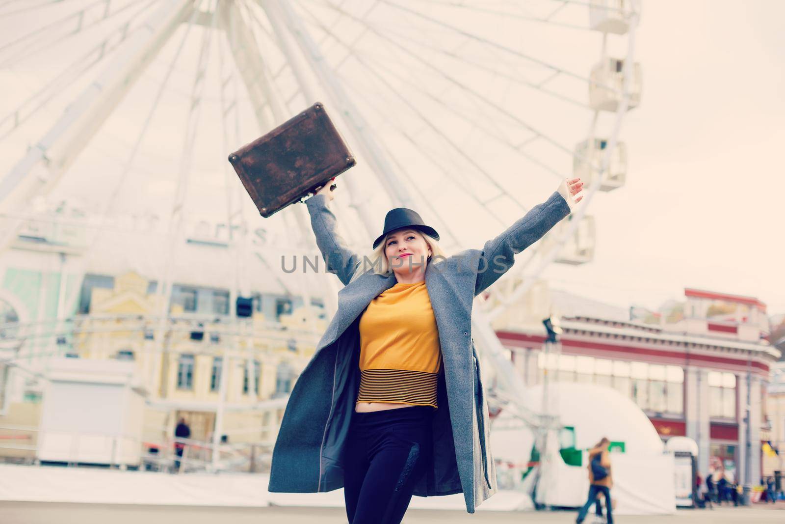 The young girl walks around the city near sights. Ferris wheel. Amusement park. autumn