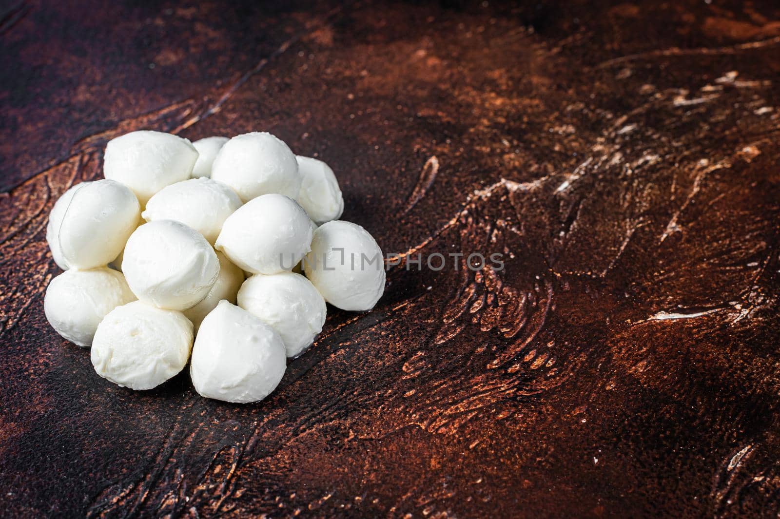 Buffalo mozzarella cheese mini balls on kitchen table. Dark background. Top view. Copy space.