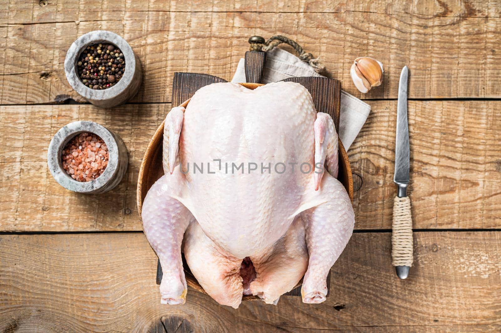 Organic chicken, raw poultry in a wooden plate. Wooden background. Top view.