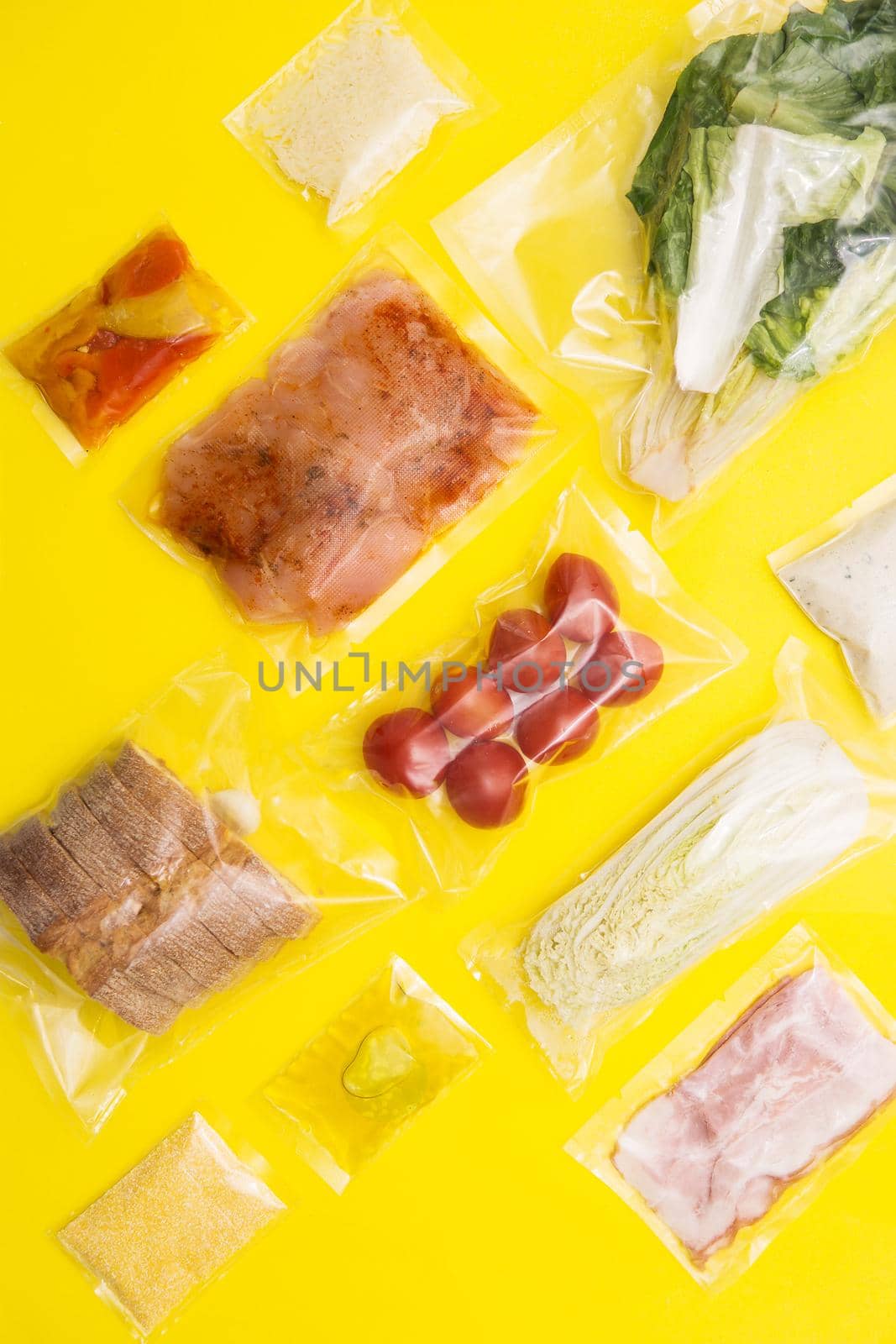 Hands holding bags of food. Salad dinner set: chicken, lettuce, tomatoes, peking cabbage, cheese, bacon, bread, olive oil sauces and spices. A set for delivering food for dinner on yellow background. I cook at home.