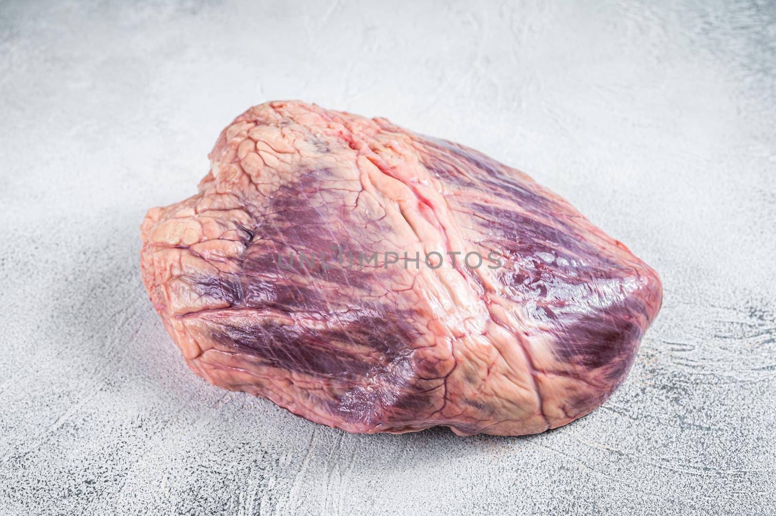 Beef or veal raw heart on a butcher table. White background. Top View.