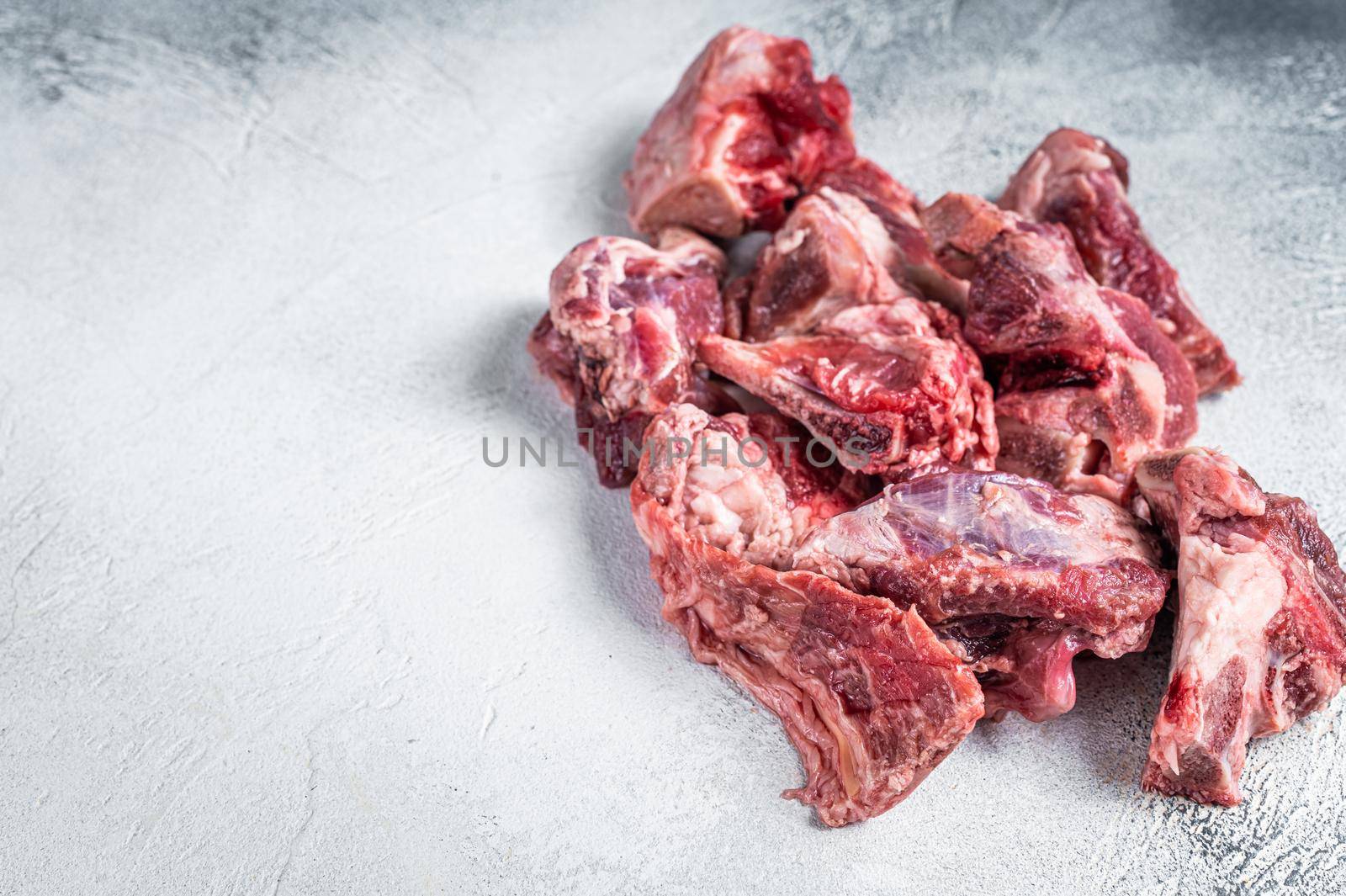 Raw lamb meat stew cuts with bone. White background. Top view. Copy space by Composter