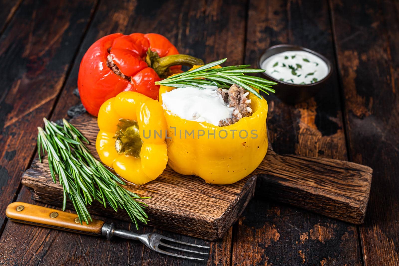 Roast bell pepper stuffed with beef meat, rice and vegetables on a wooden board. Dark wooden background. Top view.