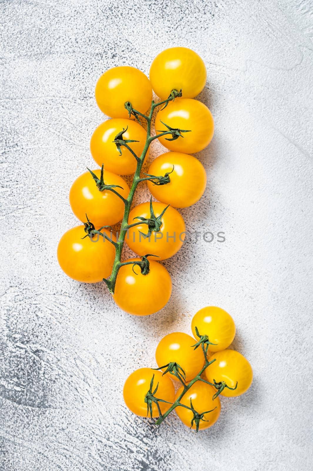 Small yellow cherry tomato on a kitchen table. White background. Top view by Composter