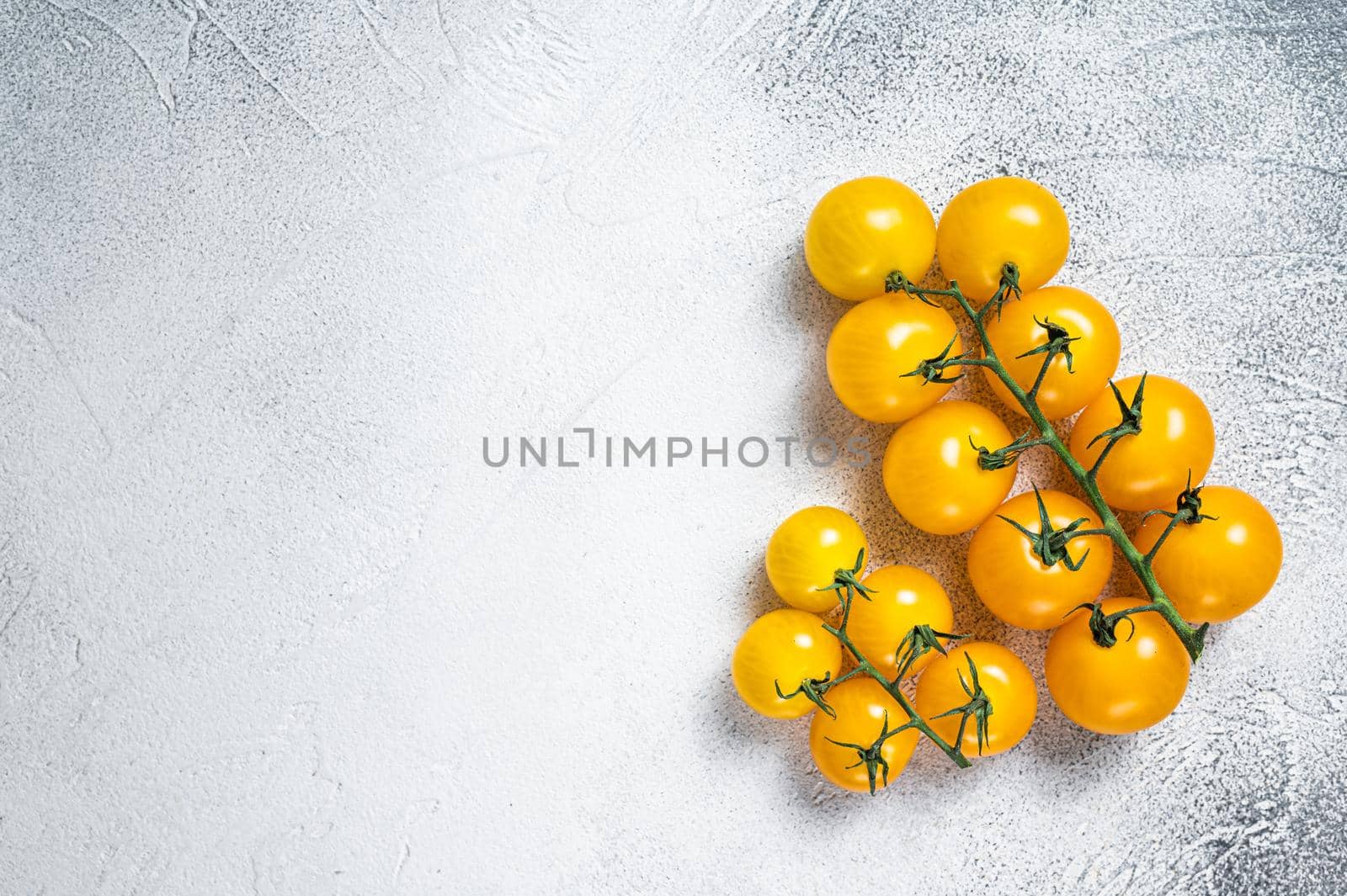 Small yellow cherry tomato on a kitchen table. White background. Top view. Copy space.