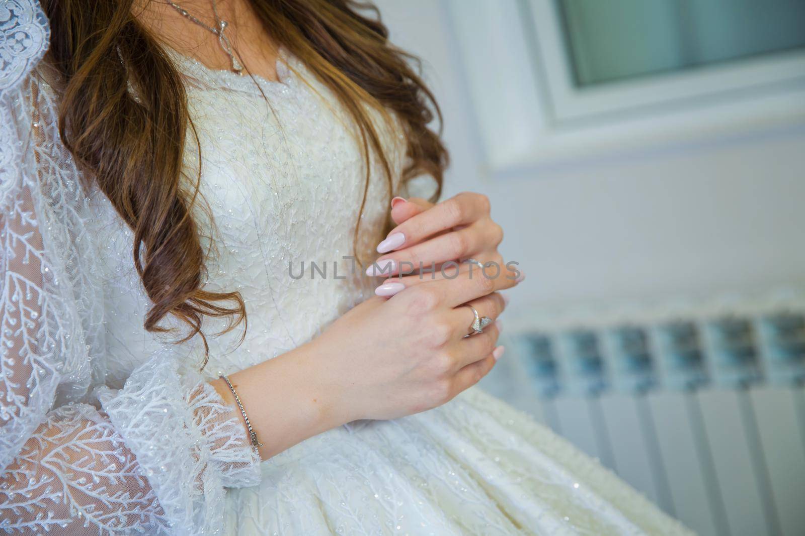 beautiful hands of the bride. Elegant female hands of bride in white dress . The bride wears a gold ring on her left hand with her right hand.