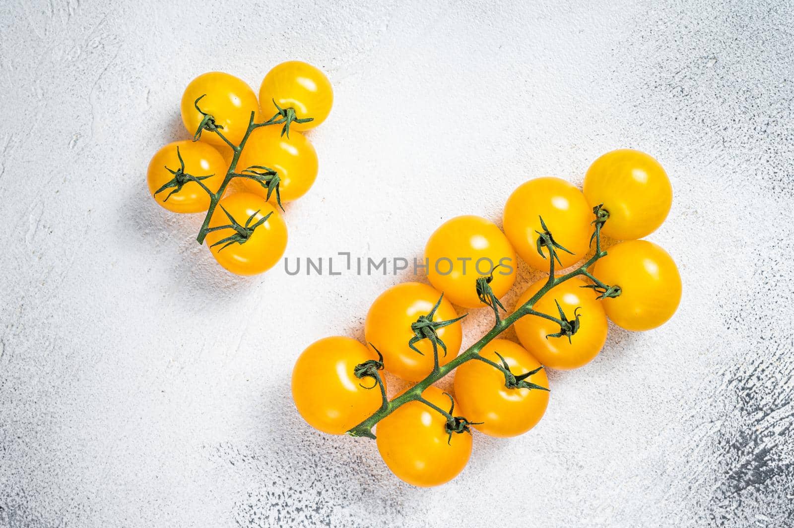 Small yellow cherry tomato on a kitchen table. White background. Top view by Composter