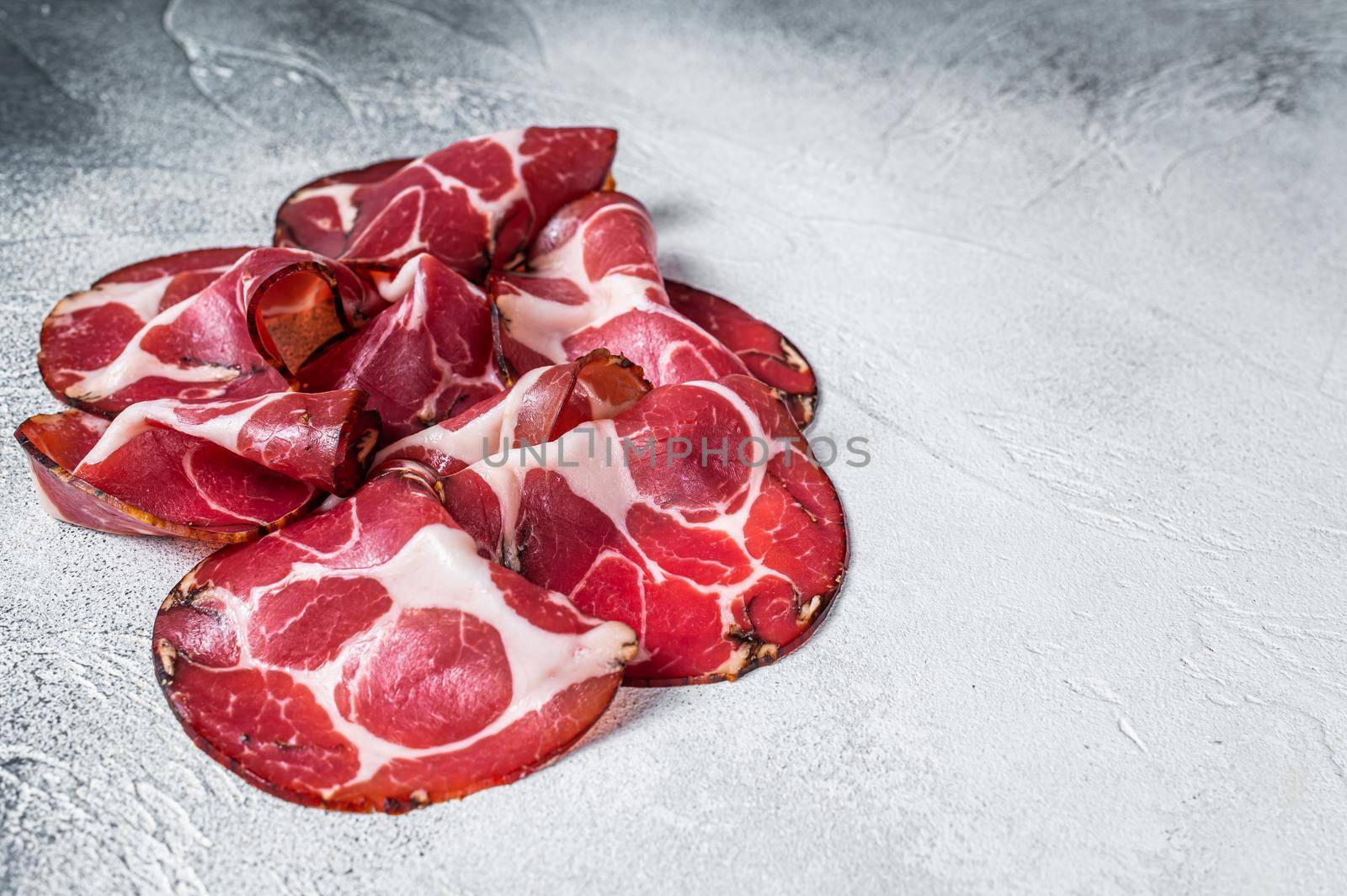 Coppa Cured ham on kitchen table. White background. Top view. Copy space by Composter