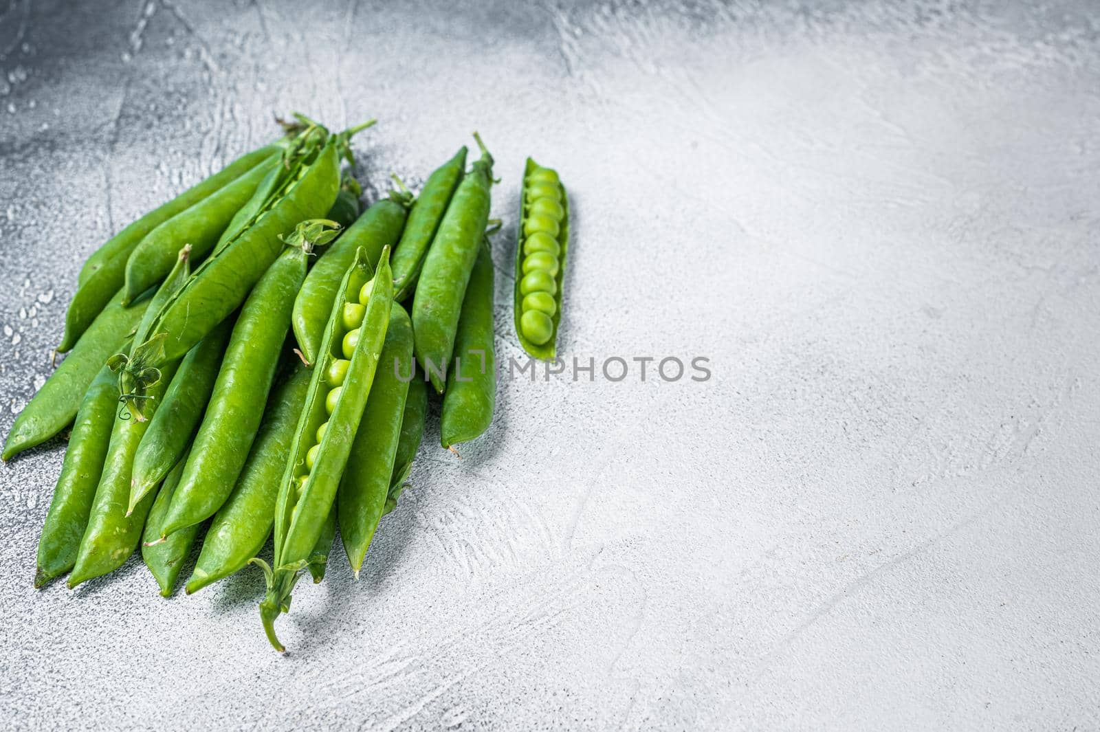 Peas and green pea pods on a kitchen table. White background. Top view. Copy space by Composter
