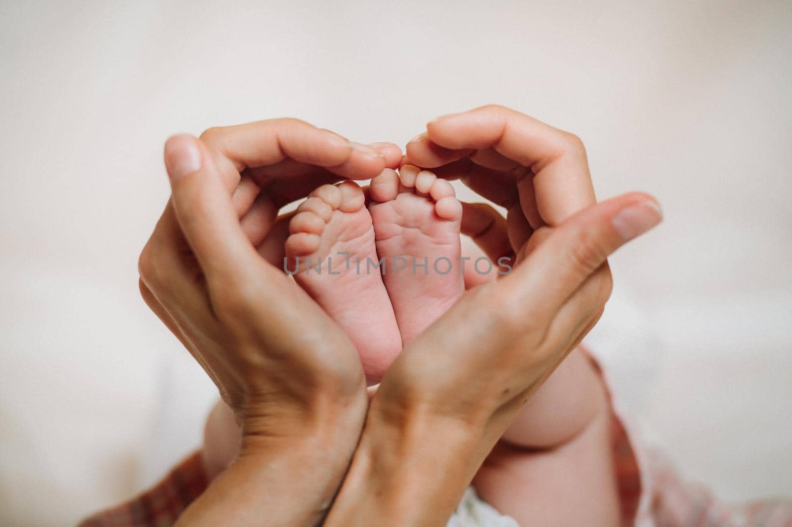 the feet of the newborn in the hands of the mother holds in the form of a heart. children's feet in the hands of the mother.