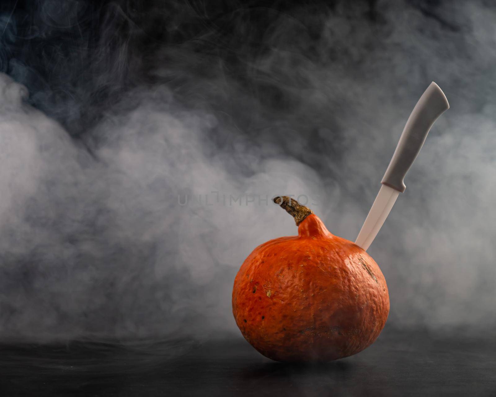 A knife in a pumpkin in the smoke. Happy Halloween