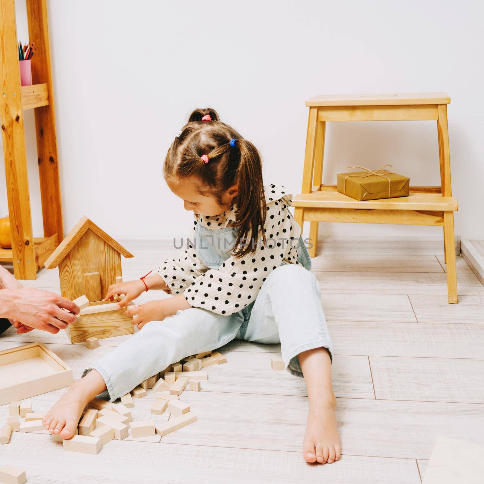 A girl and her father play a wooden constructor. by Rodnova