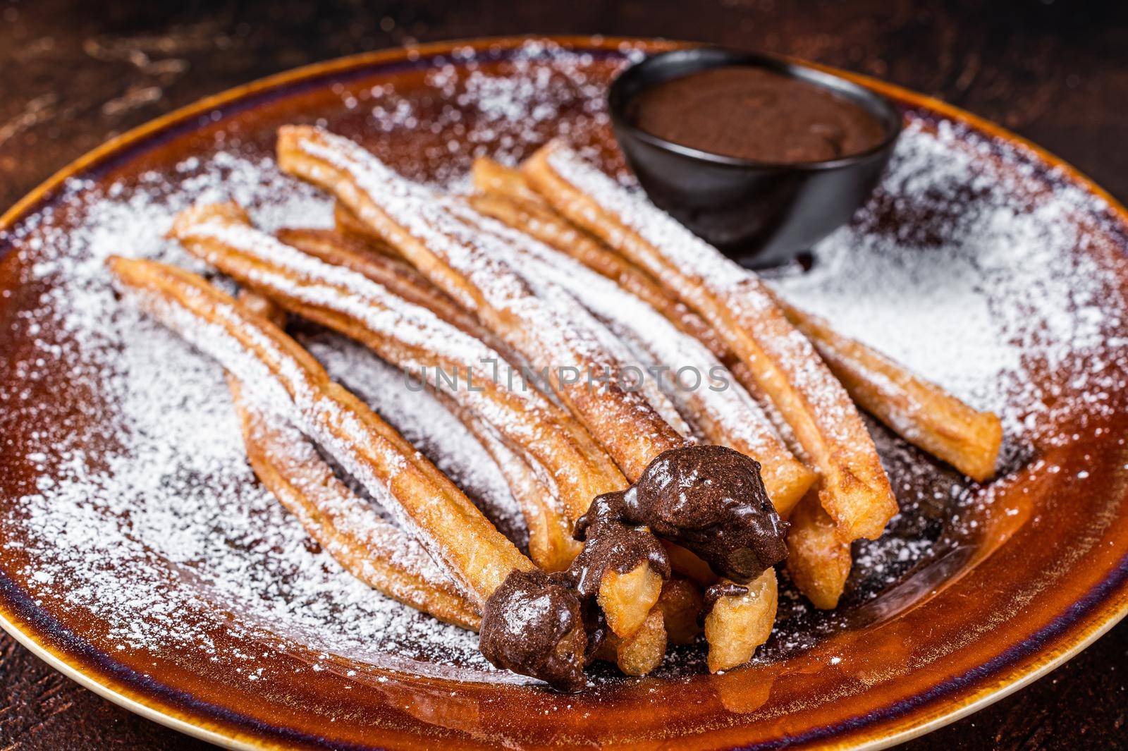 Spanish tapas churros with sugar and chocolate sauce. Dark background. Top view by Composter