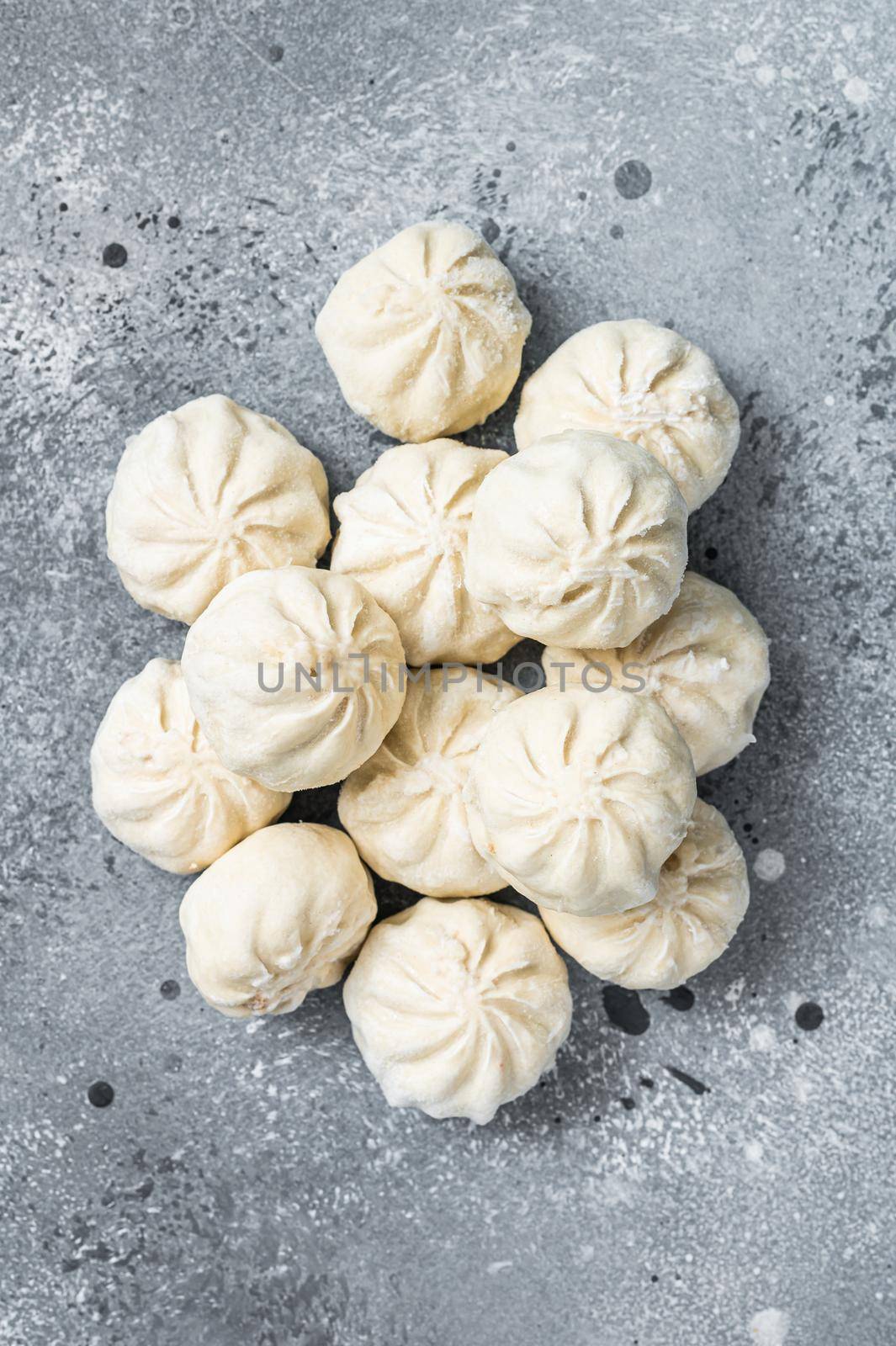 Frozen uncooked baozi dumplings stuffed with meat. Gray background. Top view.