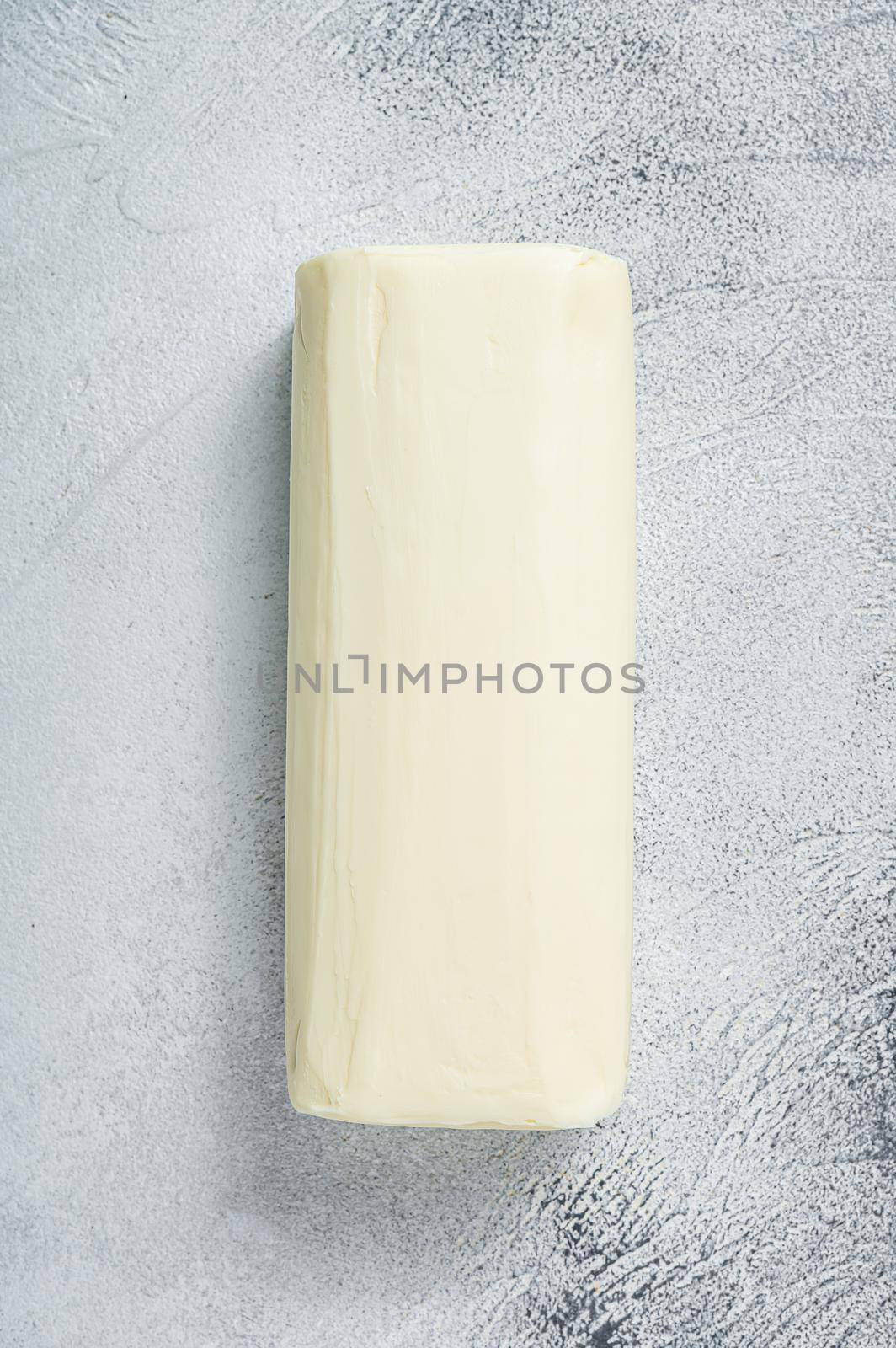 Piece of fresh butter for breakfast on kitchen table. White background. Top view.
