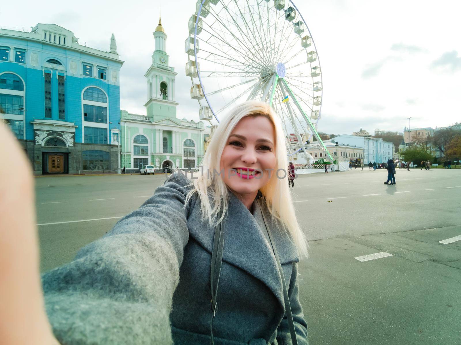 The young girl walks around the city near sights. Ferris wheel. Amusement park. autumn