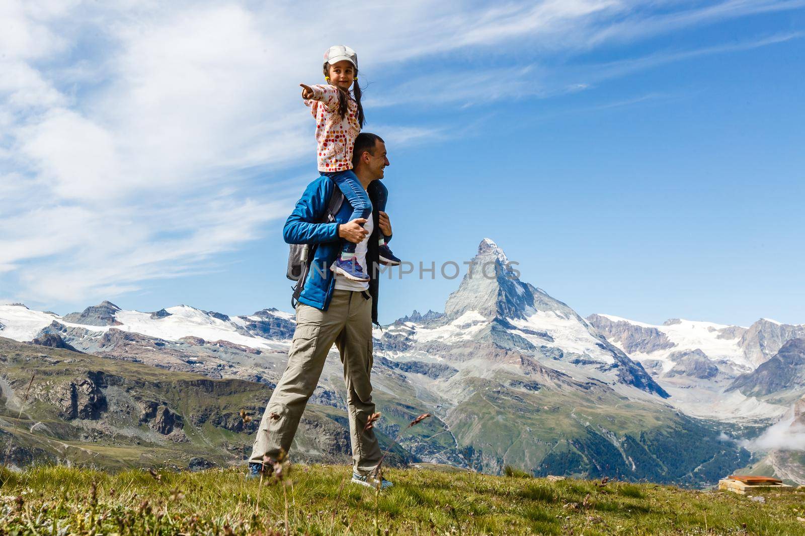 Happy family with little child doing trekking on switzerland mountain in summer time. Young people having fun in landscape nature. Concept of travel, friendly family.