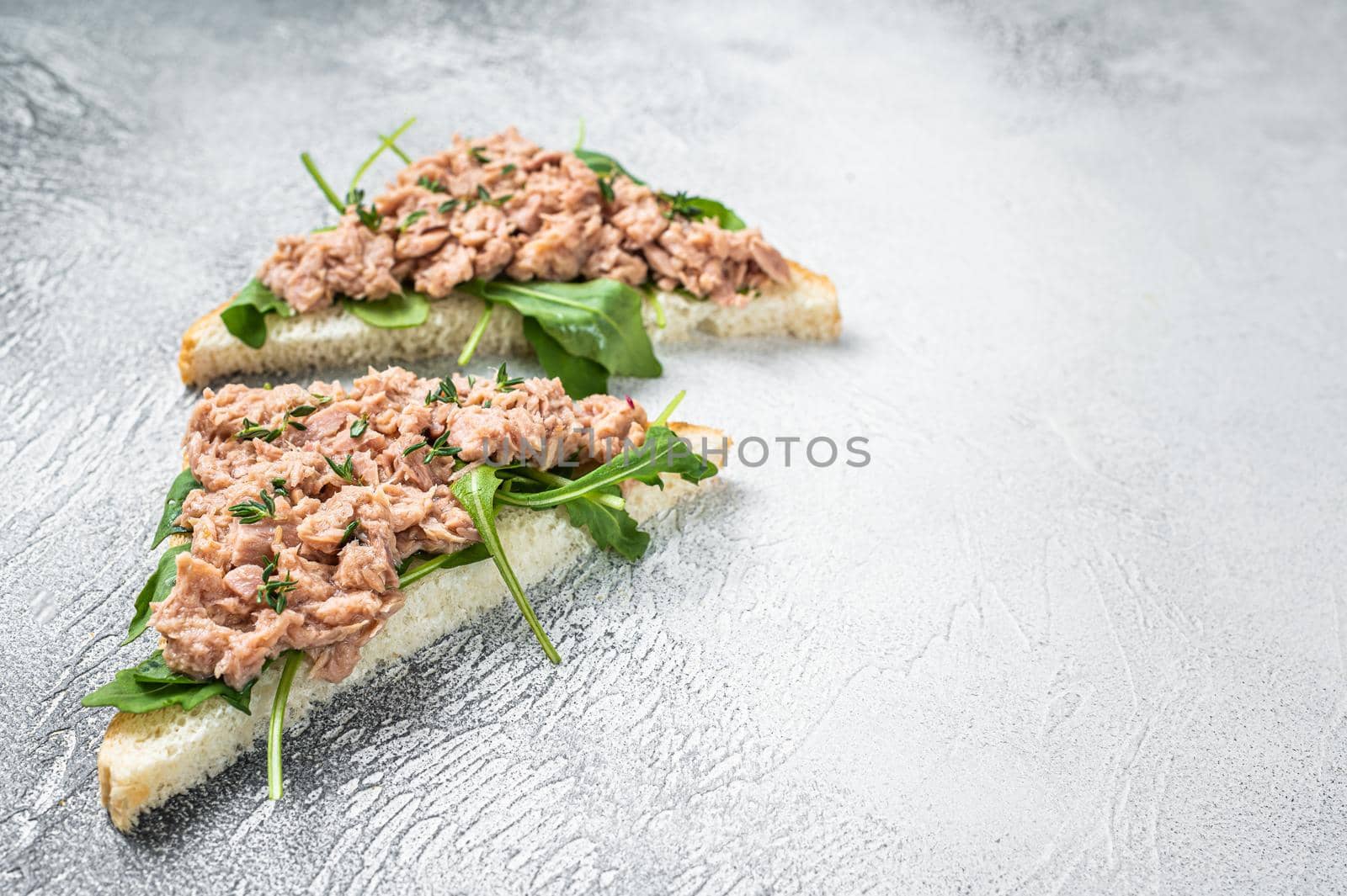 Toast with Canned Tuna fish and arugula. White background. Top view. Copy space by Composter