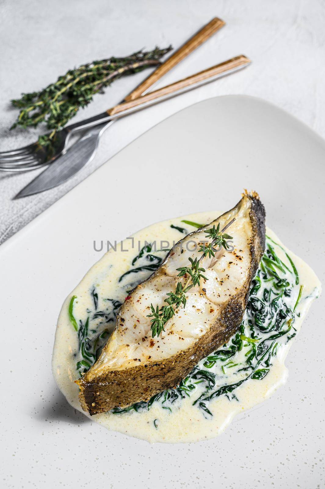 Baked Halibut fish steak with spinach. White background. Top view by Composter