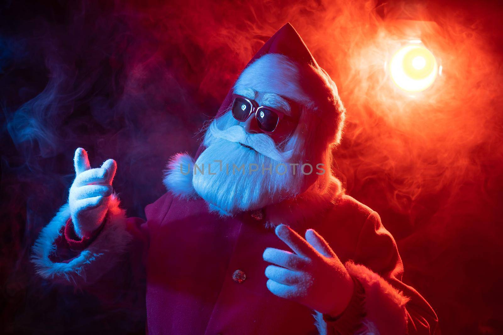 Santa claus in sunglasses in red-blue smoke. Party for Christmas