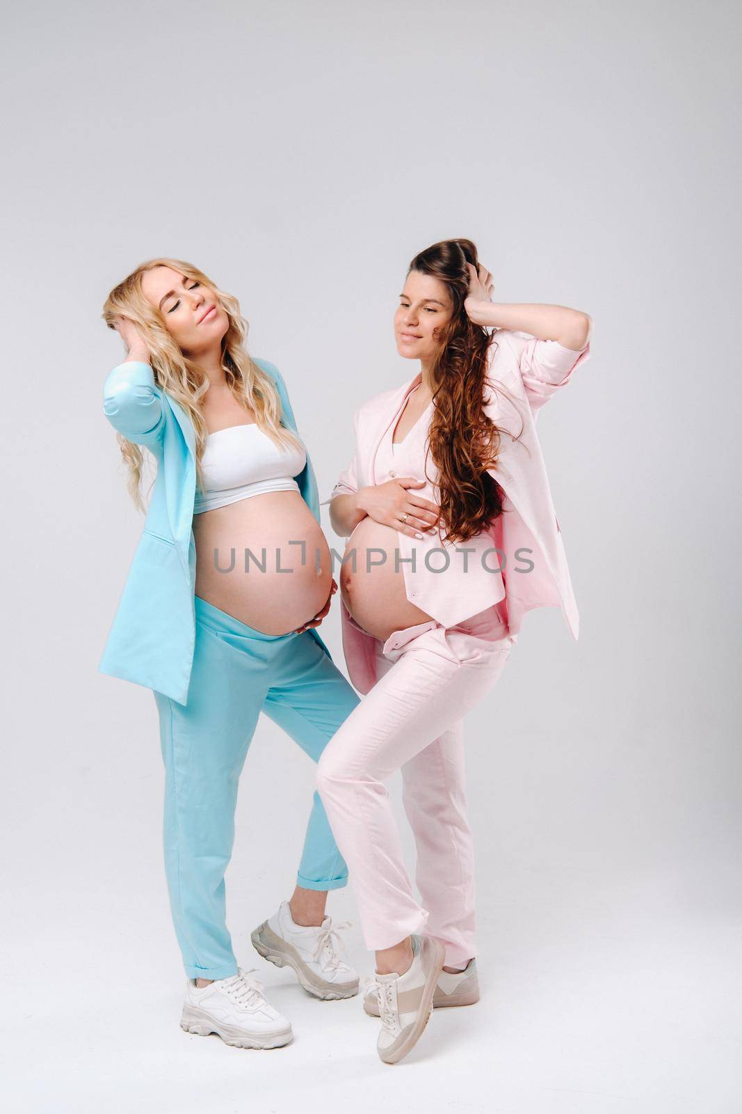 Two pregnant women with big bellies in suits on a gray background by Lobachad