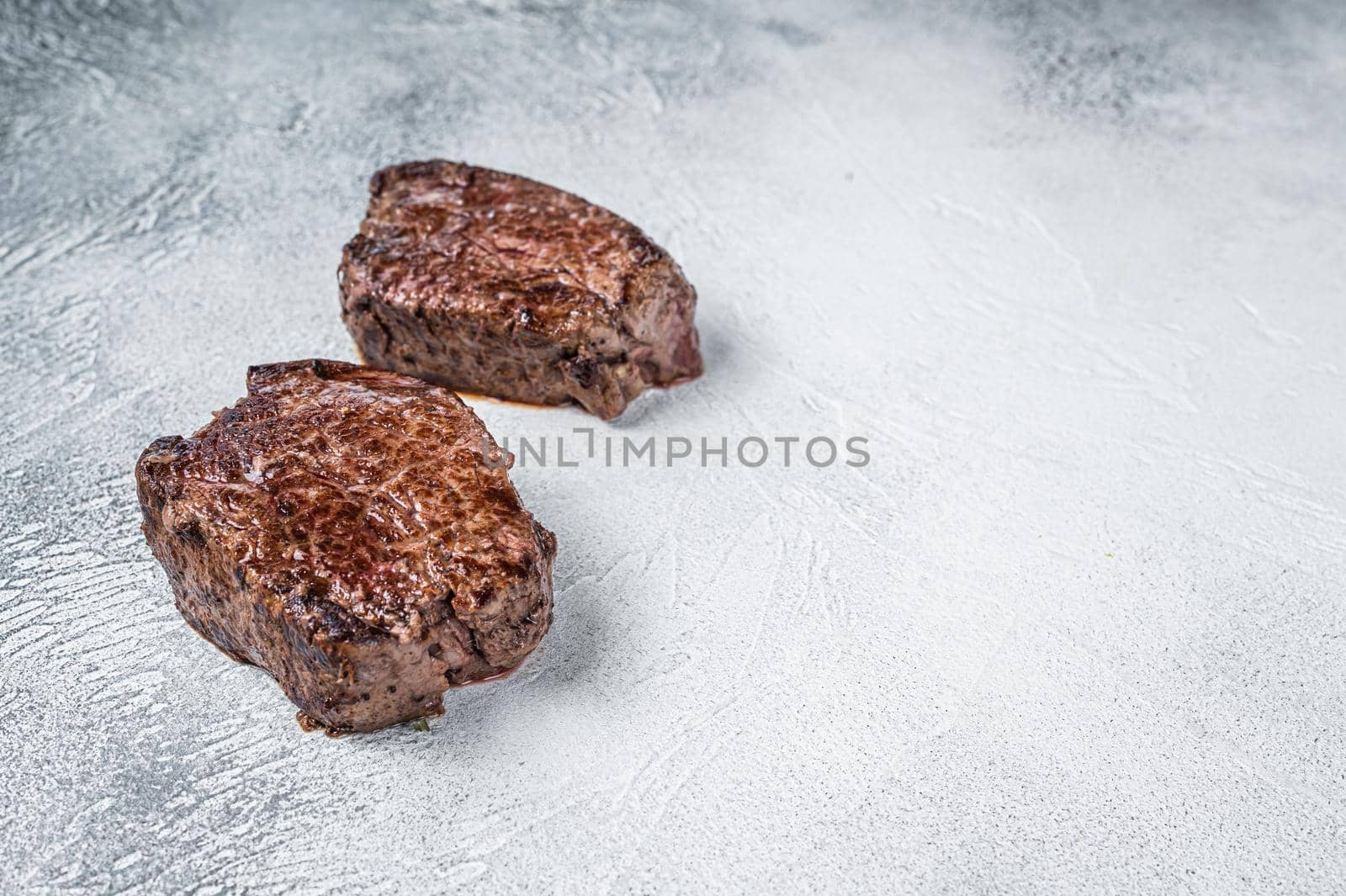 Grilled fillet mignon or tenderloin beef steak on kitchen table. White background. Top view. Copy space by Composter