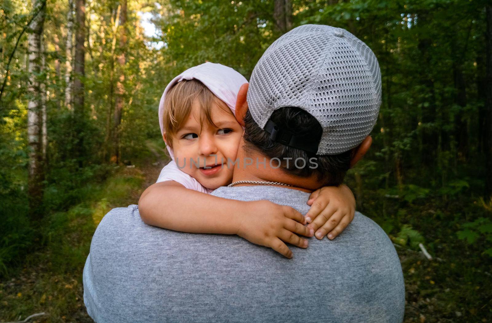 little cute toddler in dad's arms hugs his neck in the park. a happy family. father's day by Mariaprovector