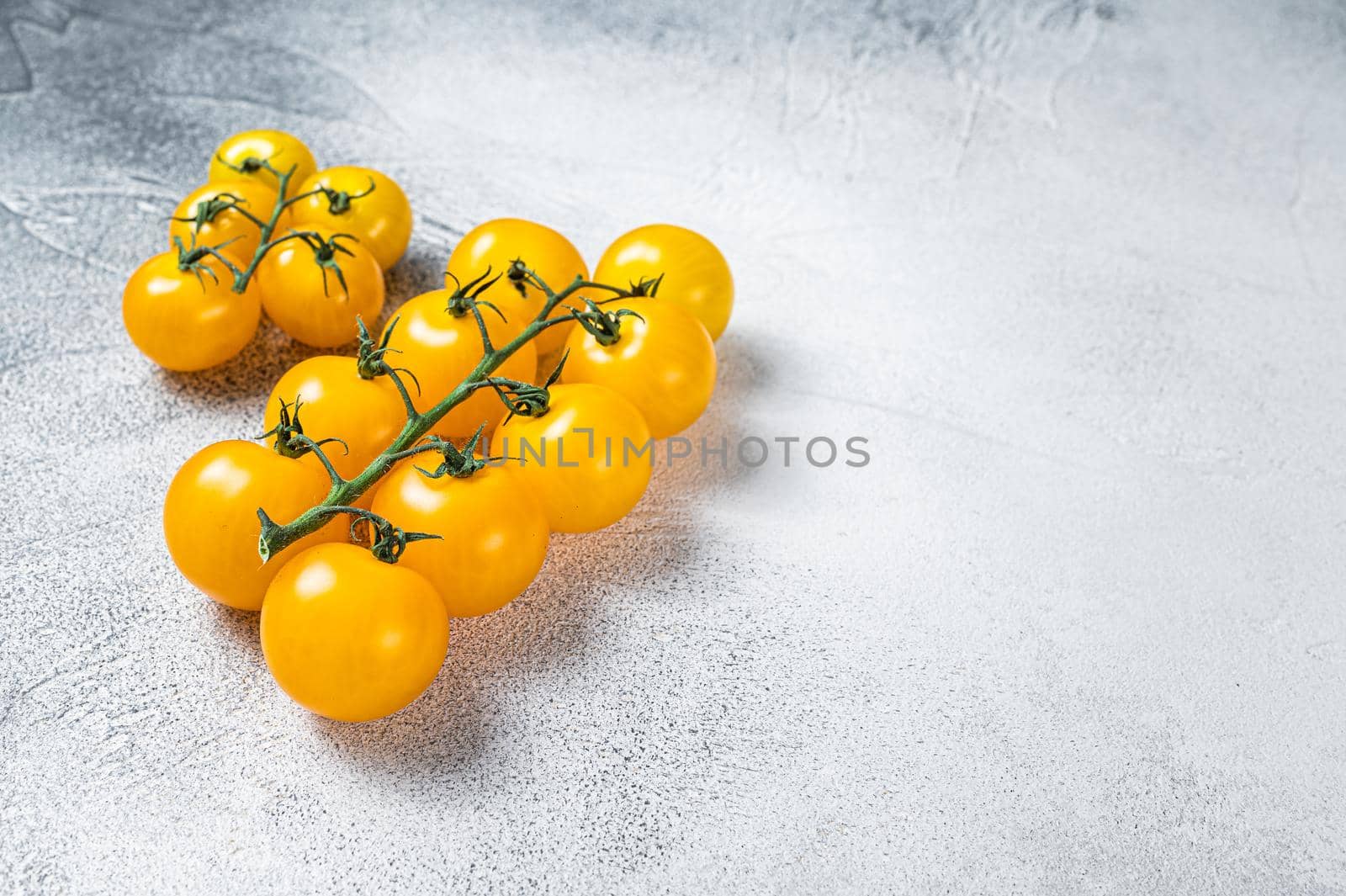 Small yellow cherry tomato on a kitchen table. White background. Top view. Copy space by Composter