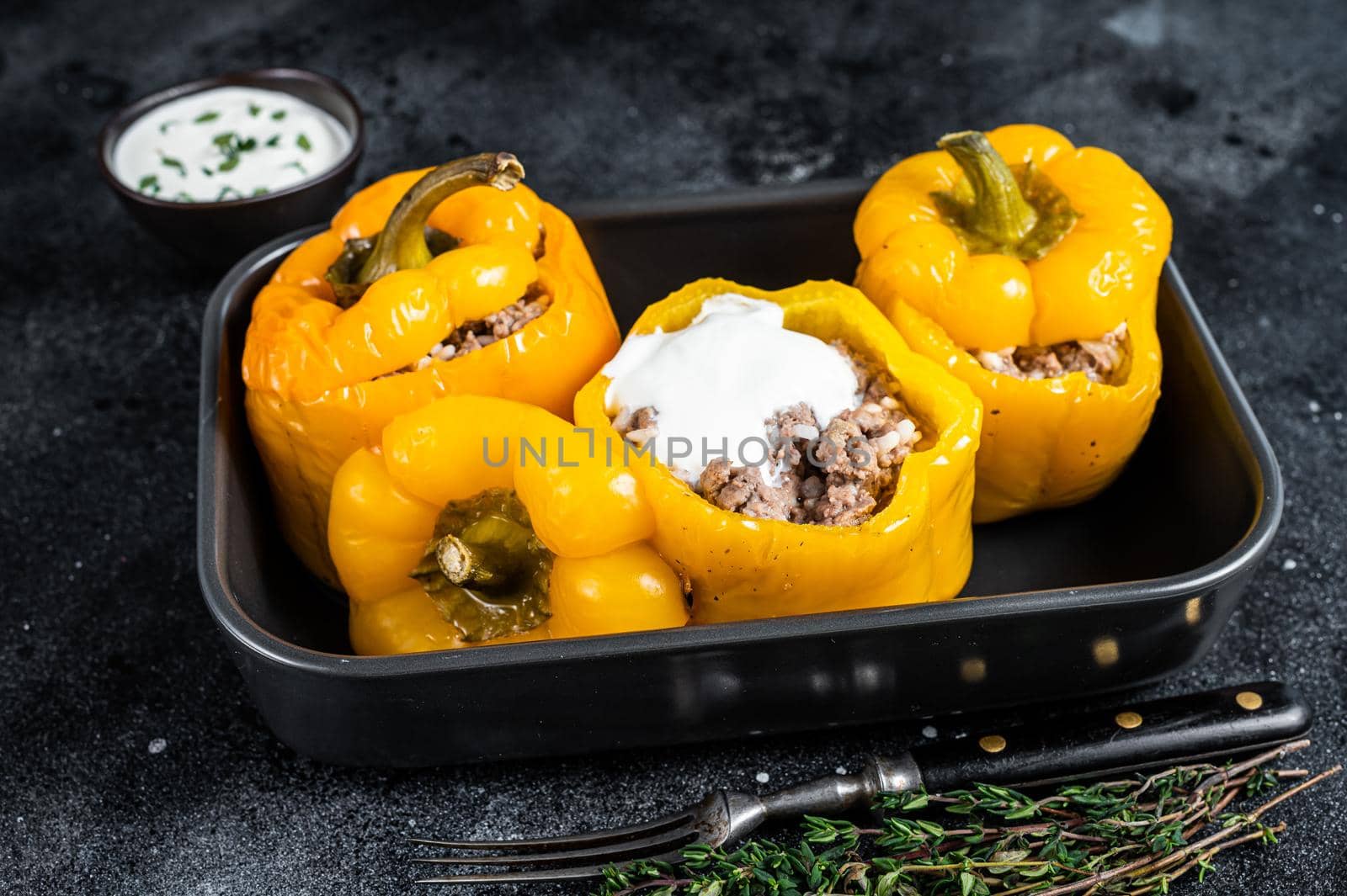 Baked yellow Sweet bell pepper stuffed with beef meat, rice and vegetables. Black background. Top view by Composter