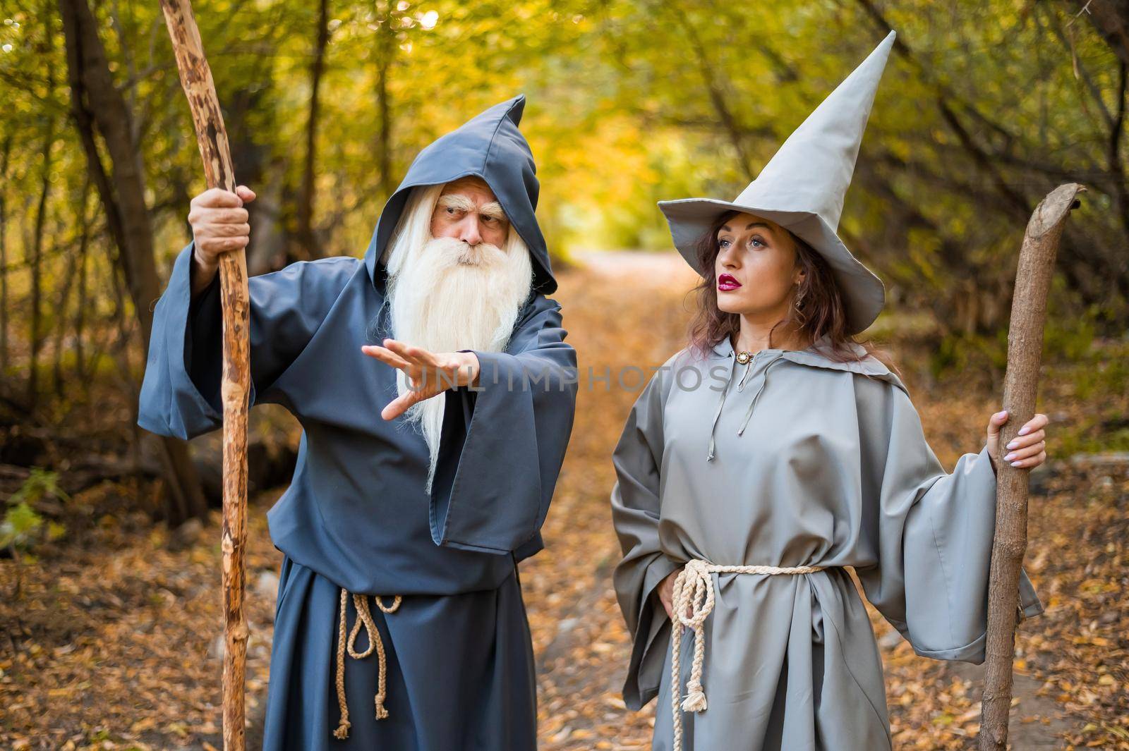 Wizard and sorceress in the autumn forest. Elderly man and woman in carnival costumes for halloween by mrwed54