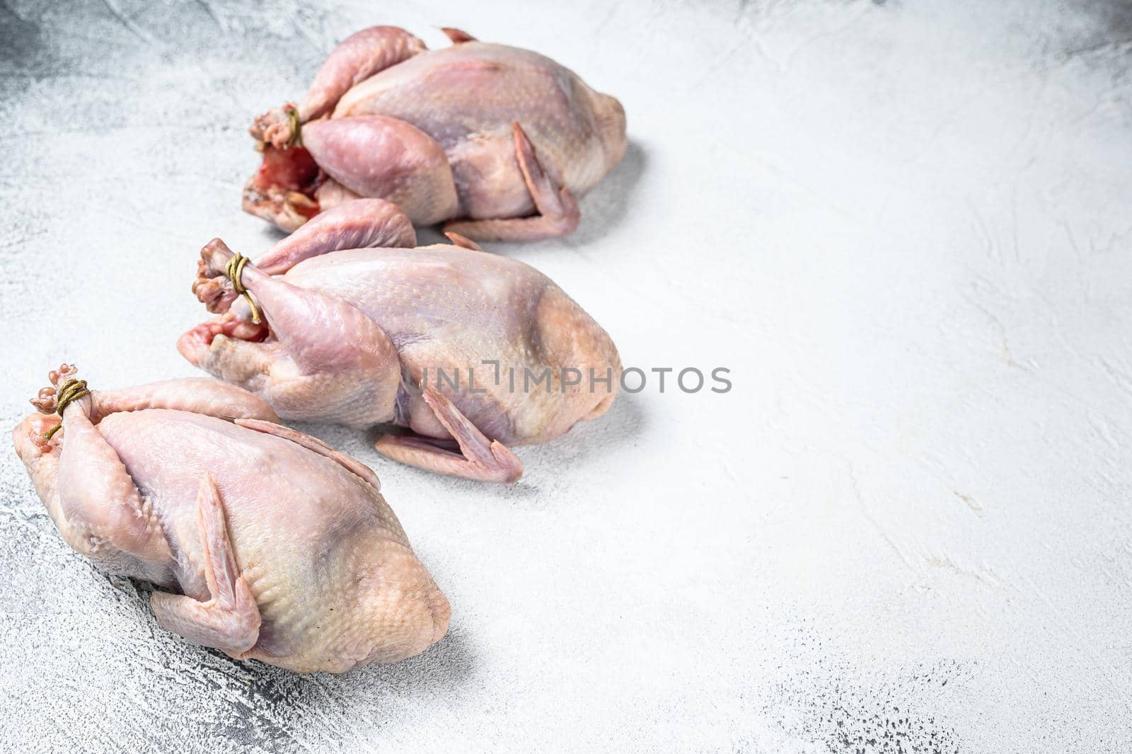 Raw quails on a kitchen table. White background. Top view. Copy space.