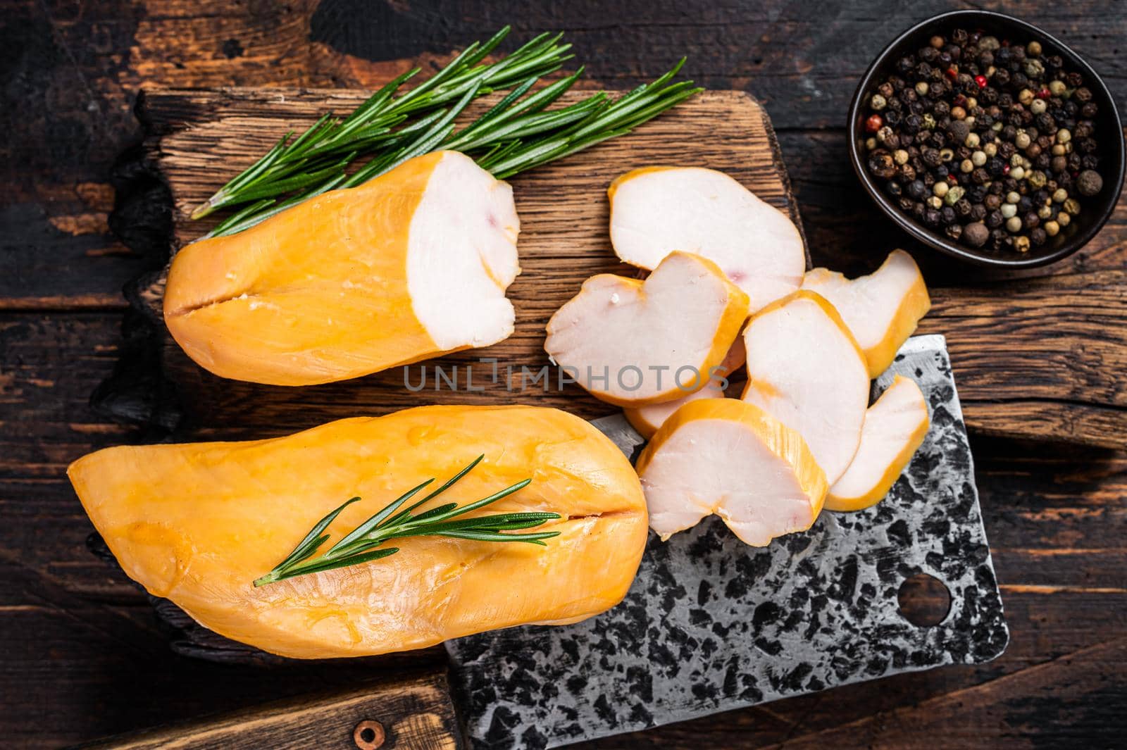 Sliced Smoked chicken breast fillet meat on a butcher board. Dark wooden background. Top view by Composter